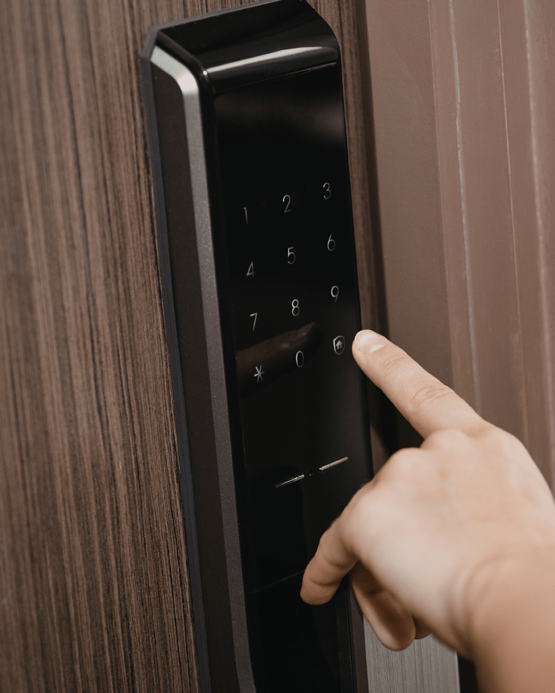 A person pressing a button on a black electronic keypad lock.