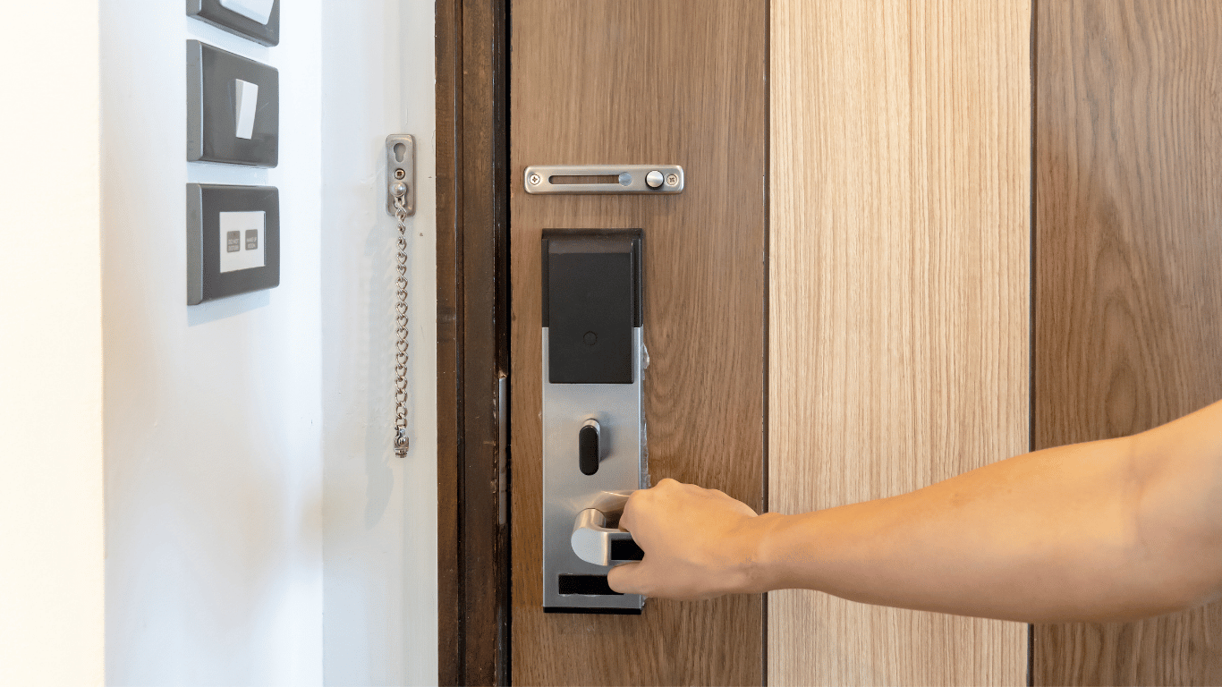 A person unlocking a wooden door with a modern electronic keypad lock.