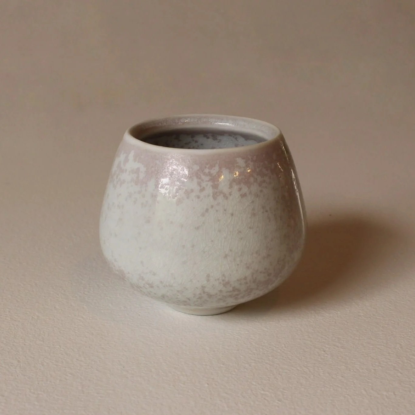 A small, rounded ceramic goblet with a crystalline celadon glaze