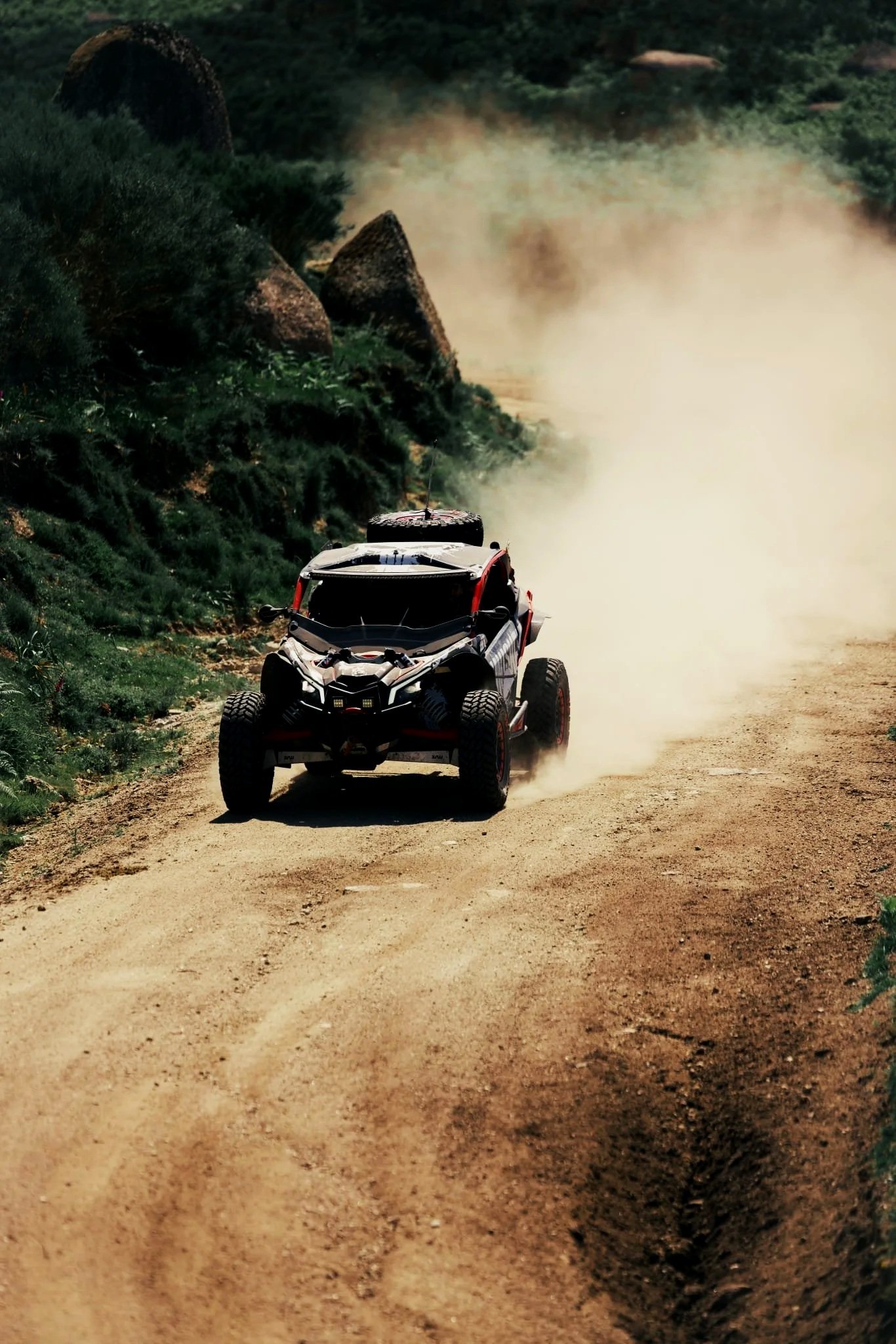 Buggy Can-Am Maverick X3 em passeio off-road nos trilhos de montanha em Braga, com poeira levantada atrás pela movimentação e velocidade em terra.