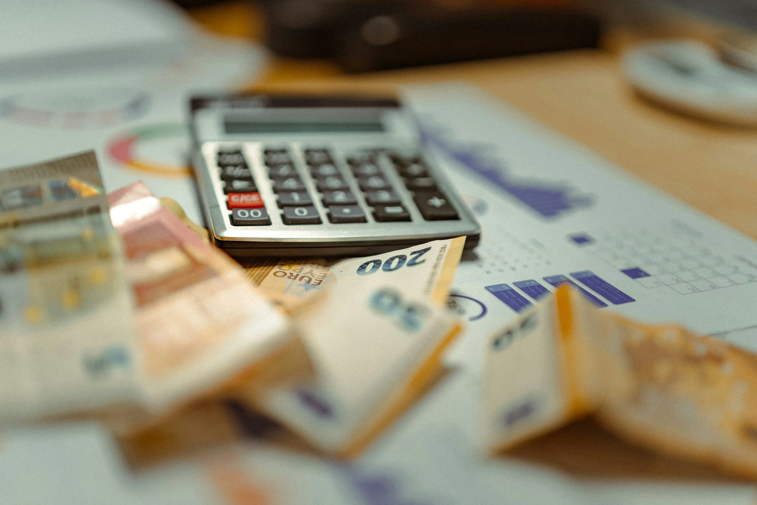Calcolatrice su fogli di carta e banconote sparse su un tavolo