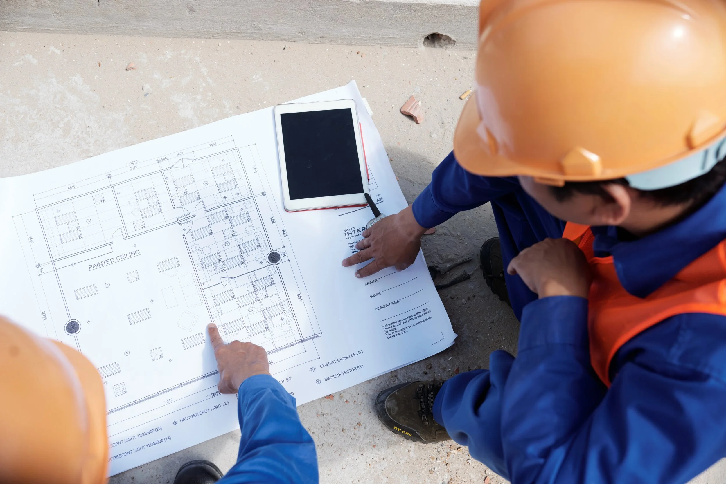 Ingegnere o architetto con casco di sicurezza consulta un progetto edilizio su carta su un cantiere.