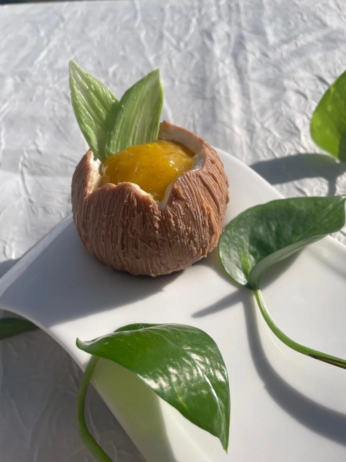 Oeuf cocotte dans une coquille en chocolat, décoré avec des feuilles vertes.