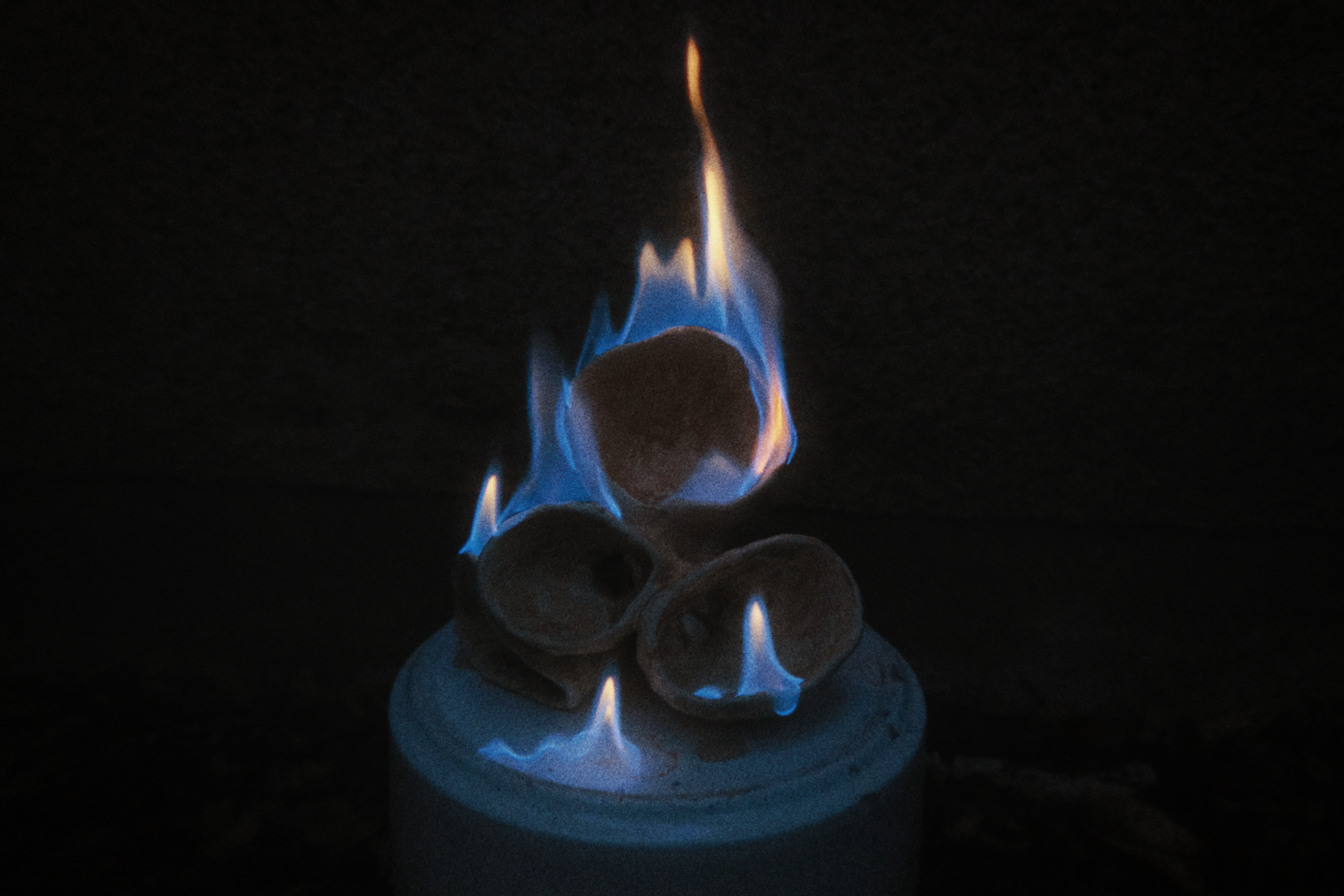 Brennende Keramik, Flammen in Blau und Orange leuchten in der Dunkelheit.