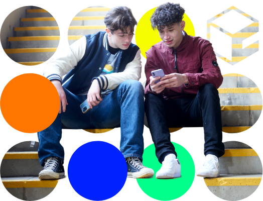 Two teenage boys sitting on stairs, looking at a smartphone together, in an urban environment.