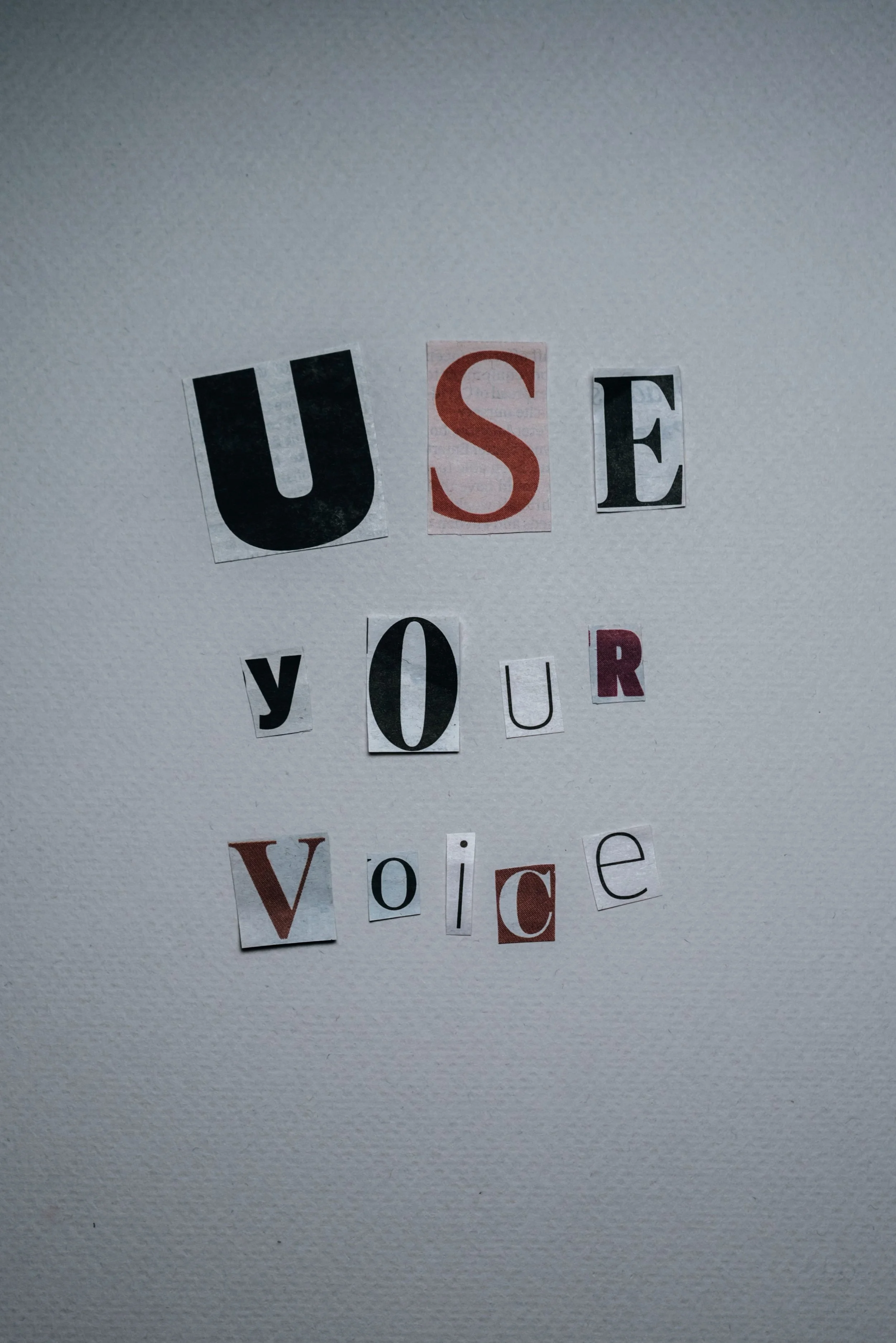 Collage spells out 'USE YOUR VOICE' on a white wall.