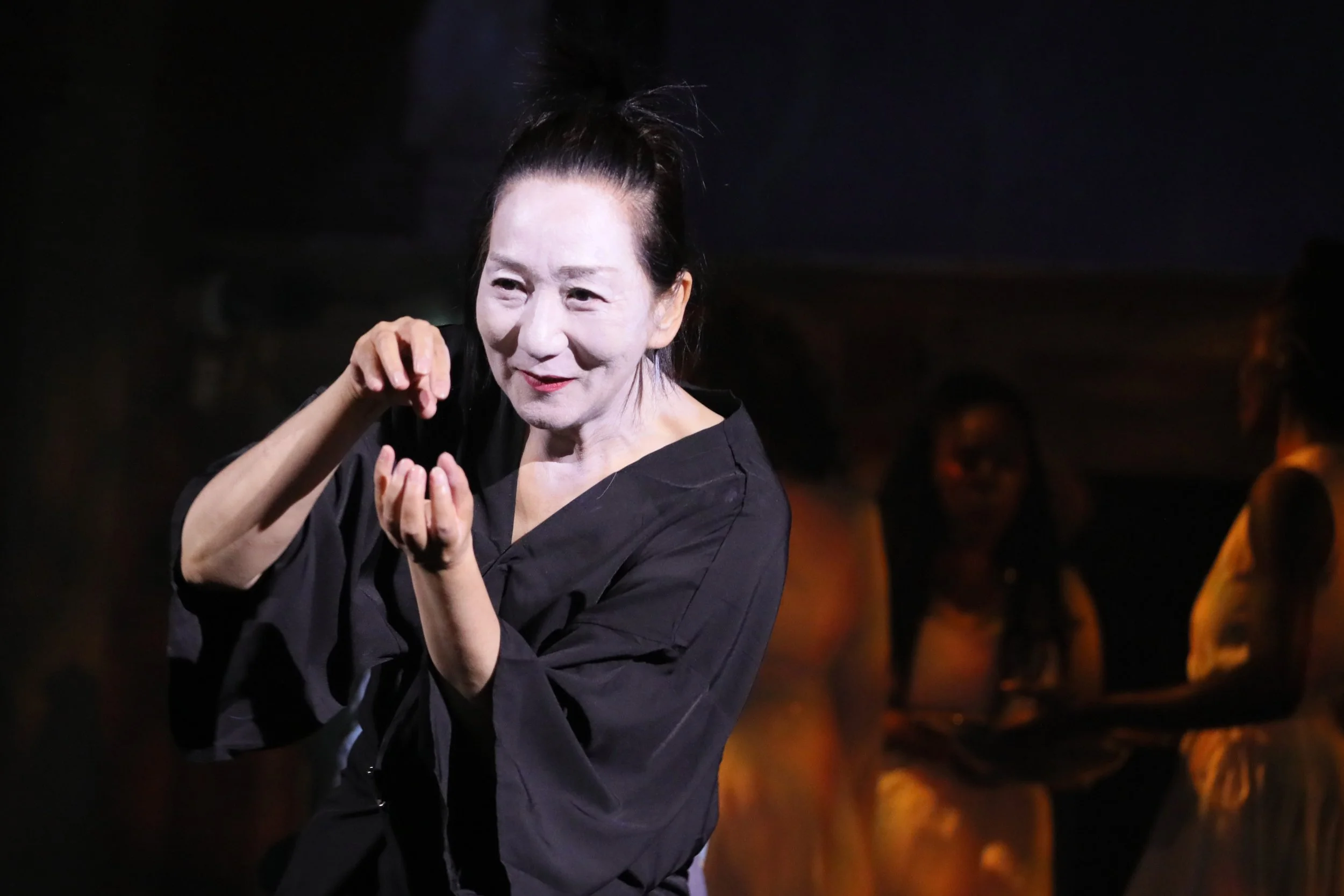 Performance artist Chisato Minamura signing in a black robe and white face paint