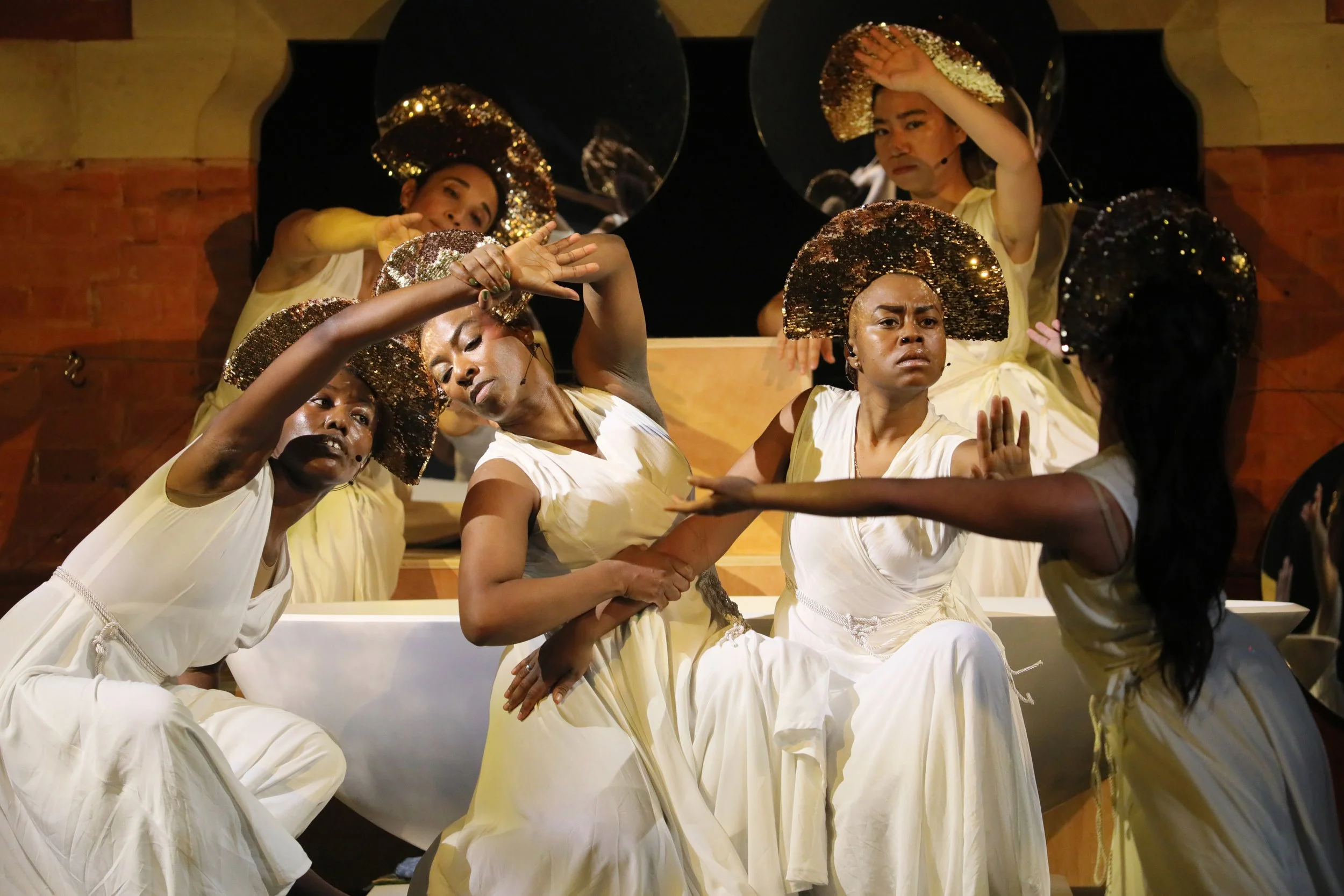The Oracle in a tableaux on stage in white gowns and gold crowns