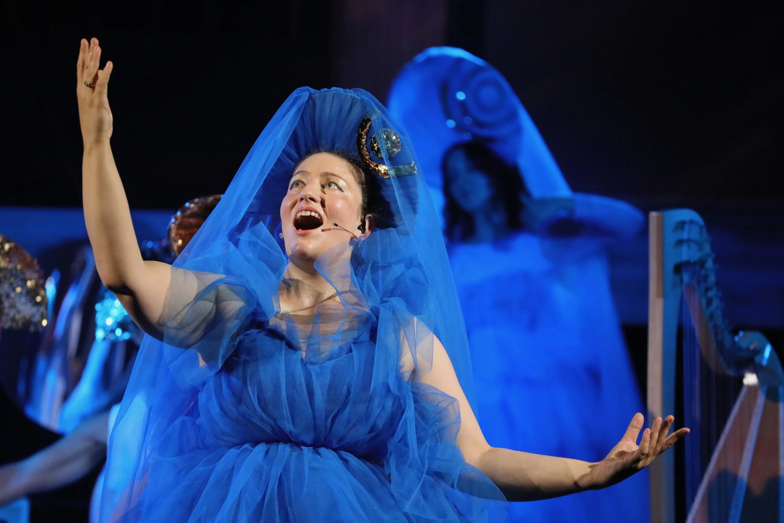 Cevanne Horrocks-Hopayian singing in a deep blue tulle dress and headpiece
