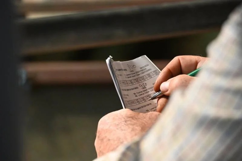 Person holding a receipt and writing on it with a pen.