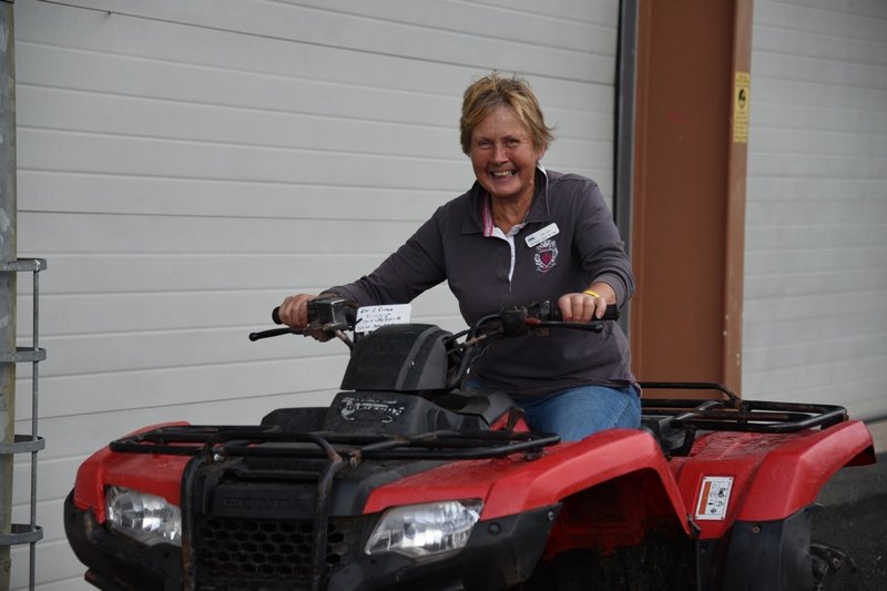 A woman smiling and sitting on a red all-terrain vehicle (ATV) indoors in front of a white garage door.