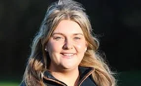 A smiling woman with blonde hair outdoors