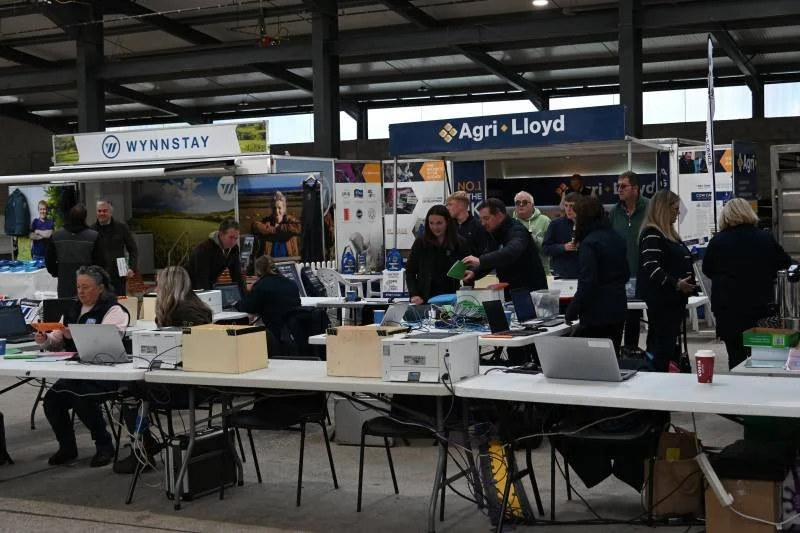 Trade show with booths and people networking, including banners for Wynnstay and Agri Lloyd.