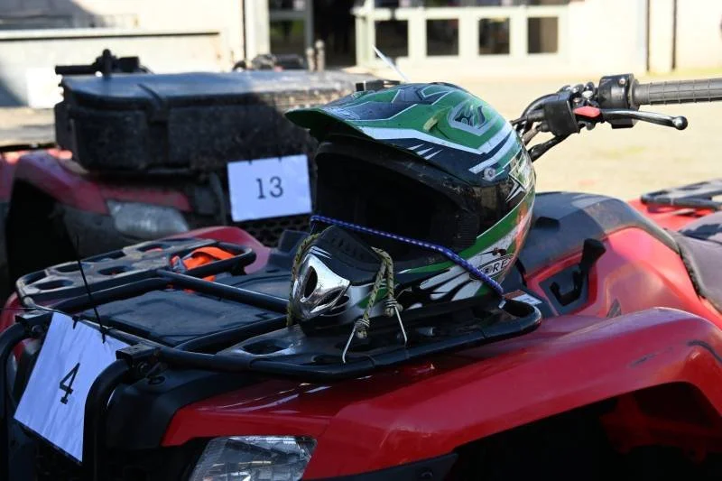 A red all-terrain vehicle (ATV) with a green motorcycle helmet and a pair of sunglasses placed on its front rack.