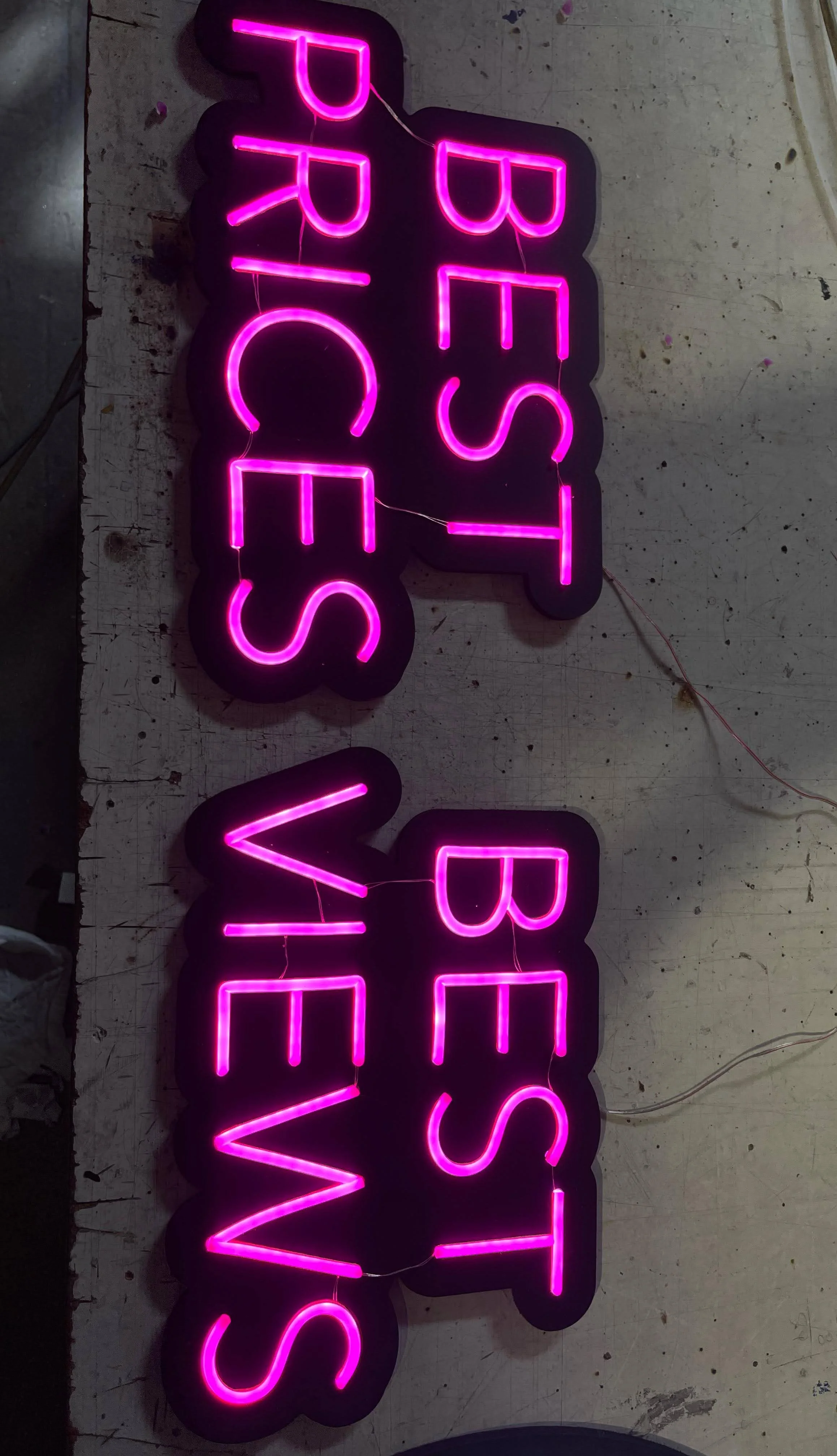 Letras de neón rosa que dicen 'BEER' y 'WINE' en un fondo oscuro.