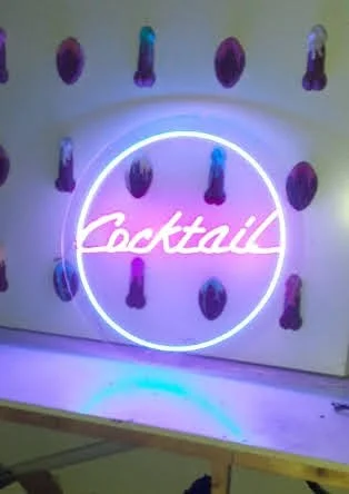 Rótulo luminoso con la palabra 'cocktail' en letras de neón y decoraciones de globos en la pared.