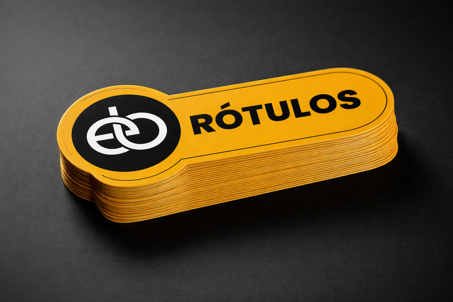 Variedad de etiquetas adhesivas amarillas con la palabra 'Rótulos' en negro y un símbolo de dos anillos entrelazados en un fondo negro.