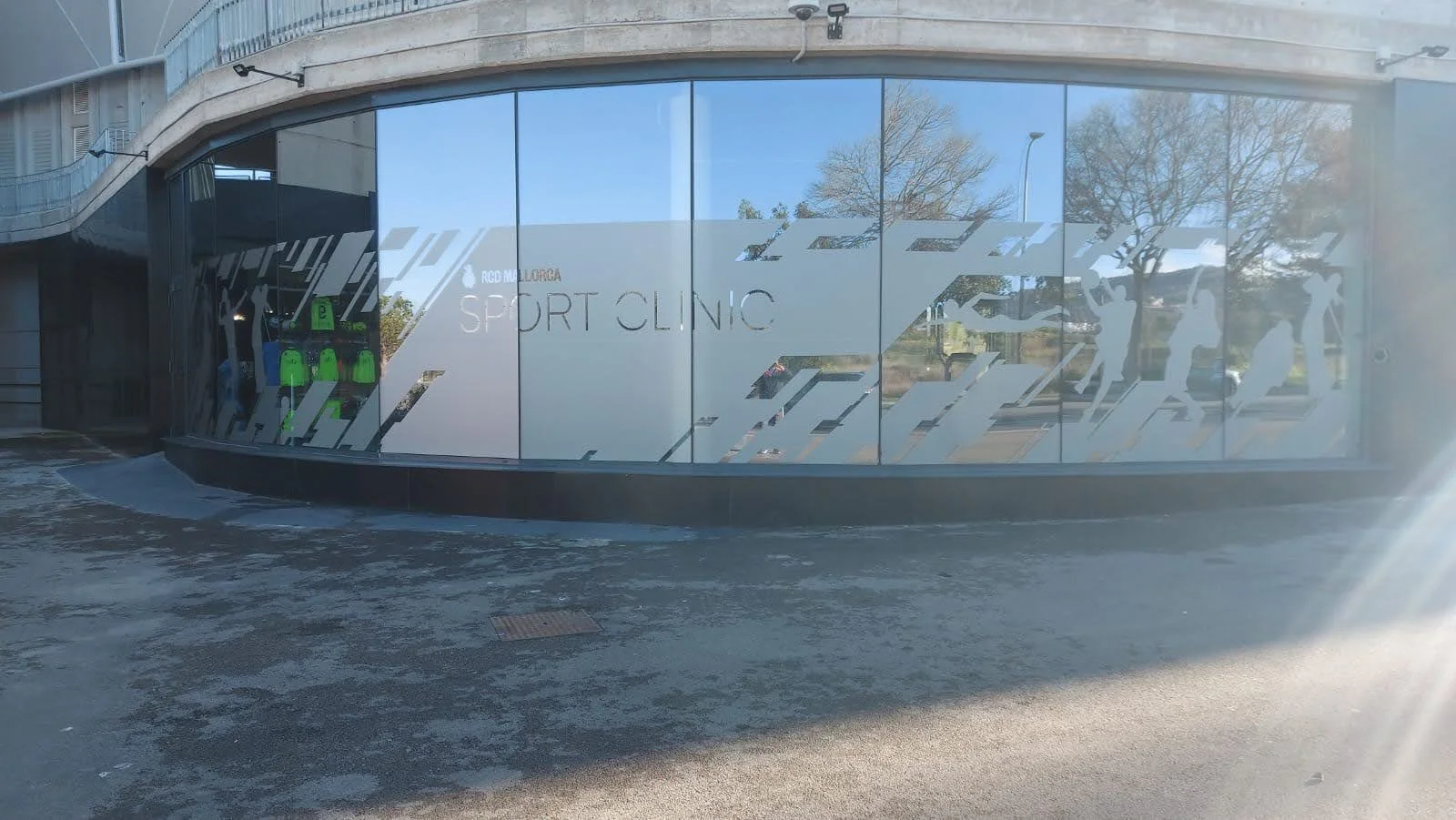 fachada de una clínica deportiva con ventanales de vidrio y siluetas de deportistas en la ventana