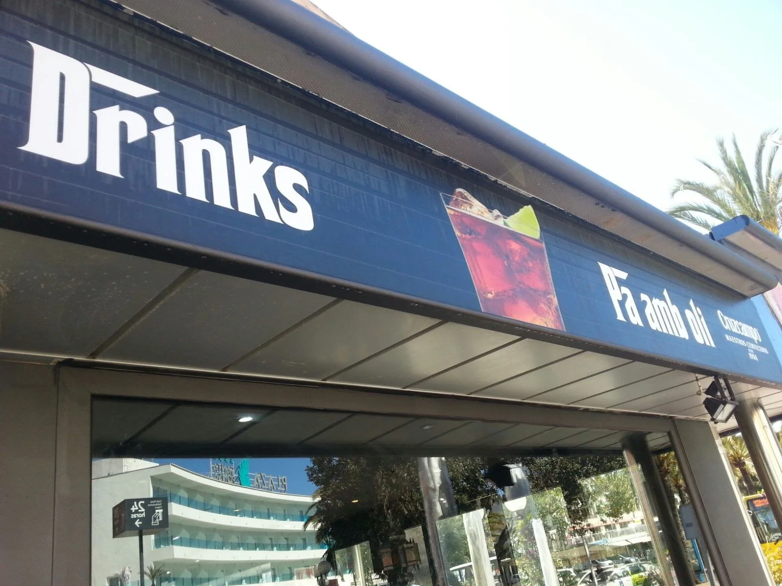  cartel azul que dice 'Drinks' y 'Famba' con una imagen de una copa con una bebida color morado y un trozo de limón