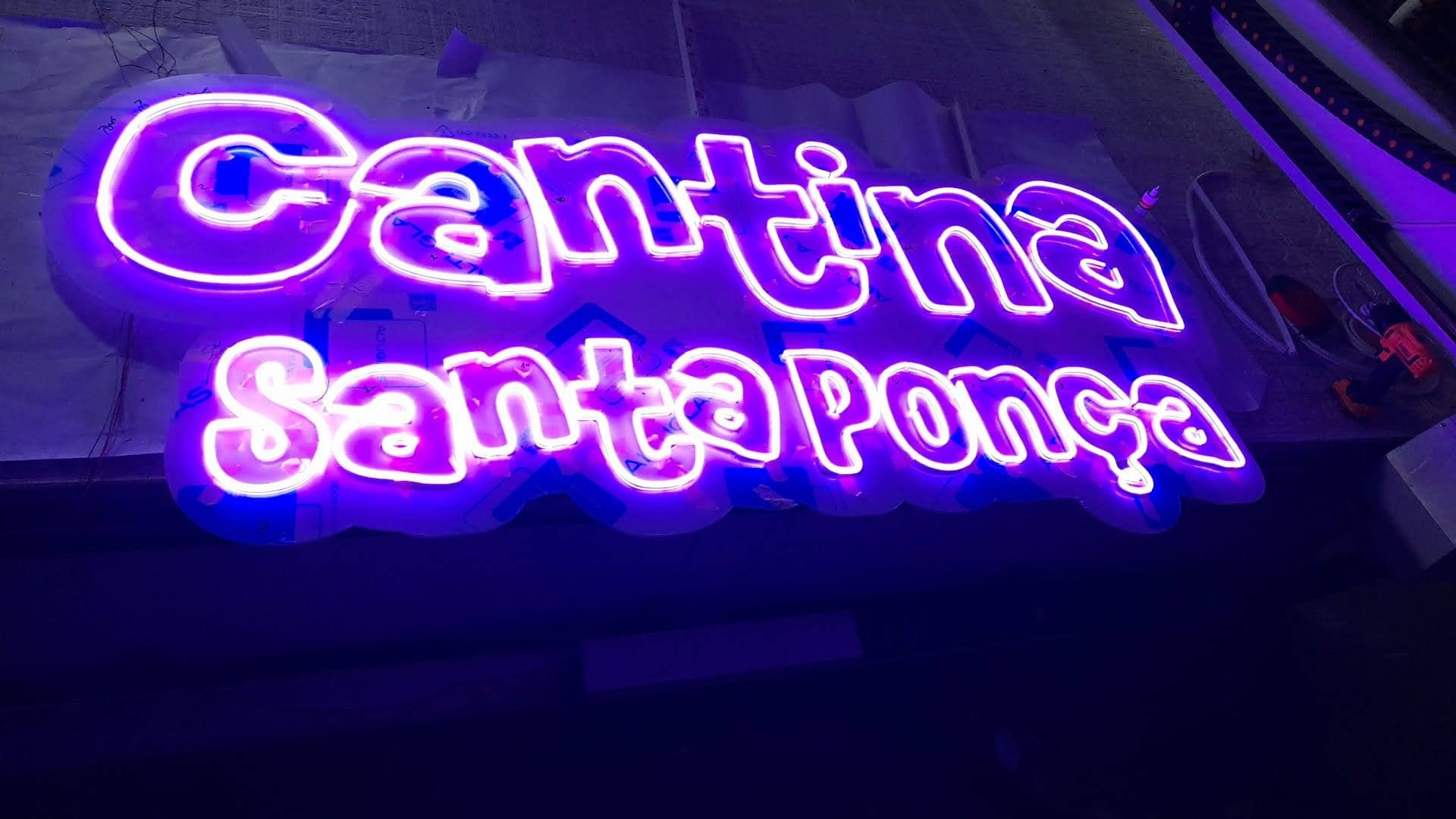 Letrero de neón que dice 'Caffeine Santes' en colores rosa y azul
