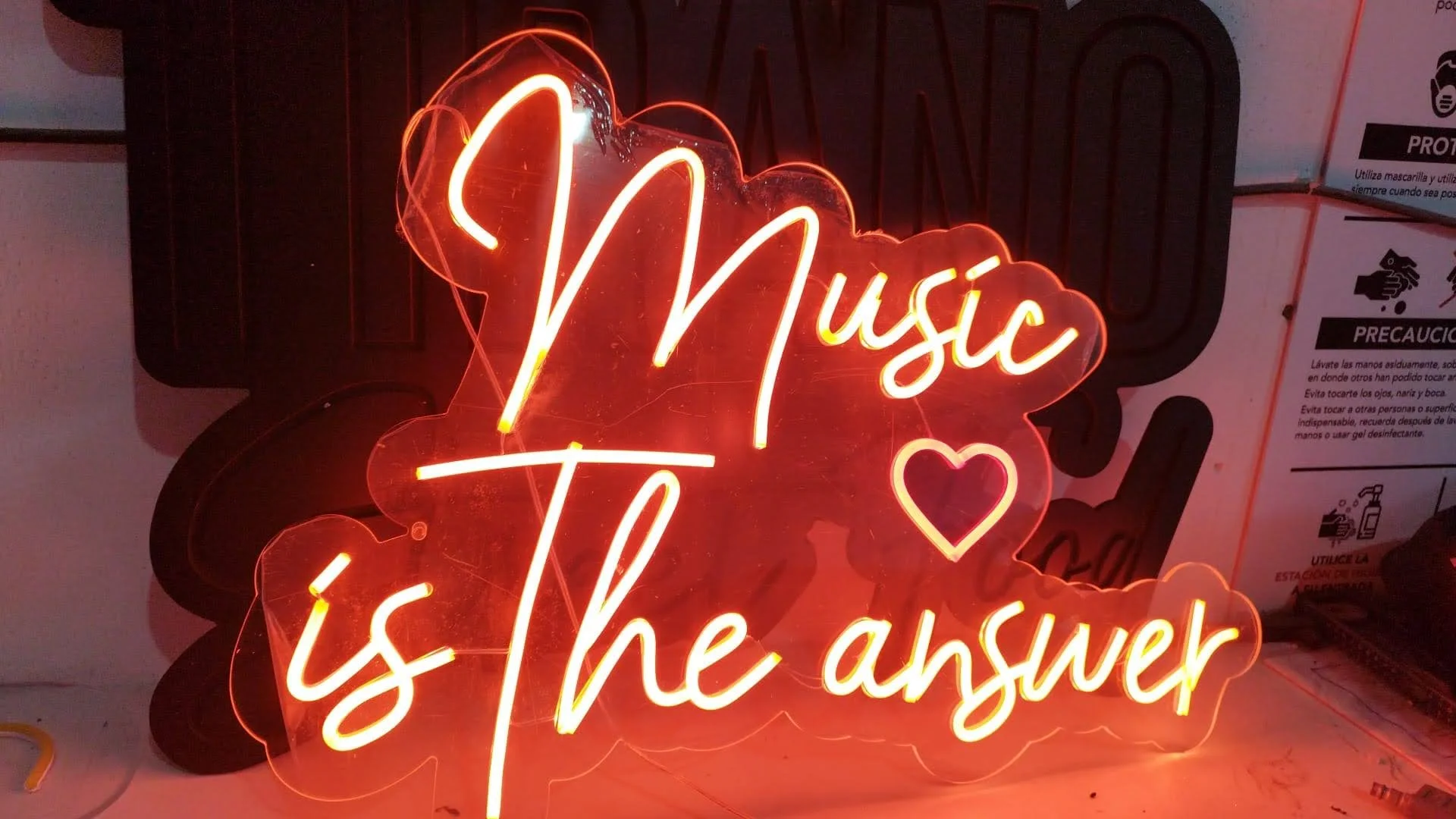 Letrero de neón con la palabra 'Music' y un corazón en color rojo, en fondo oscuro.