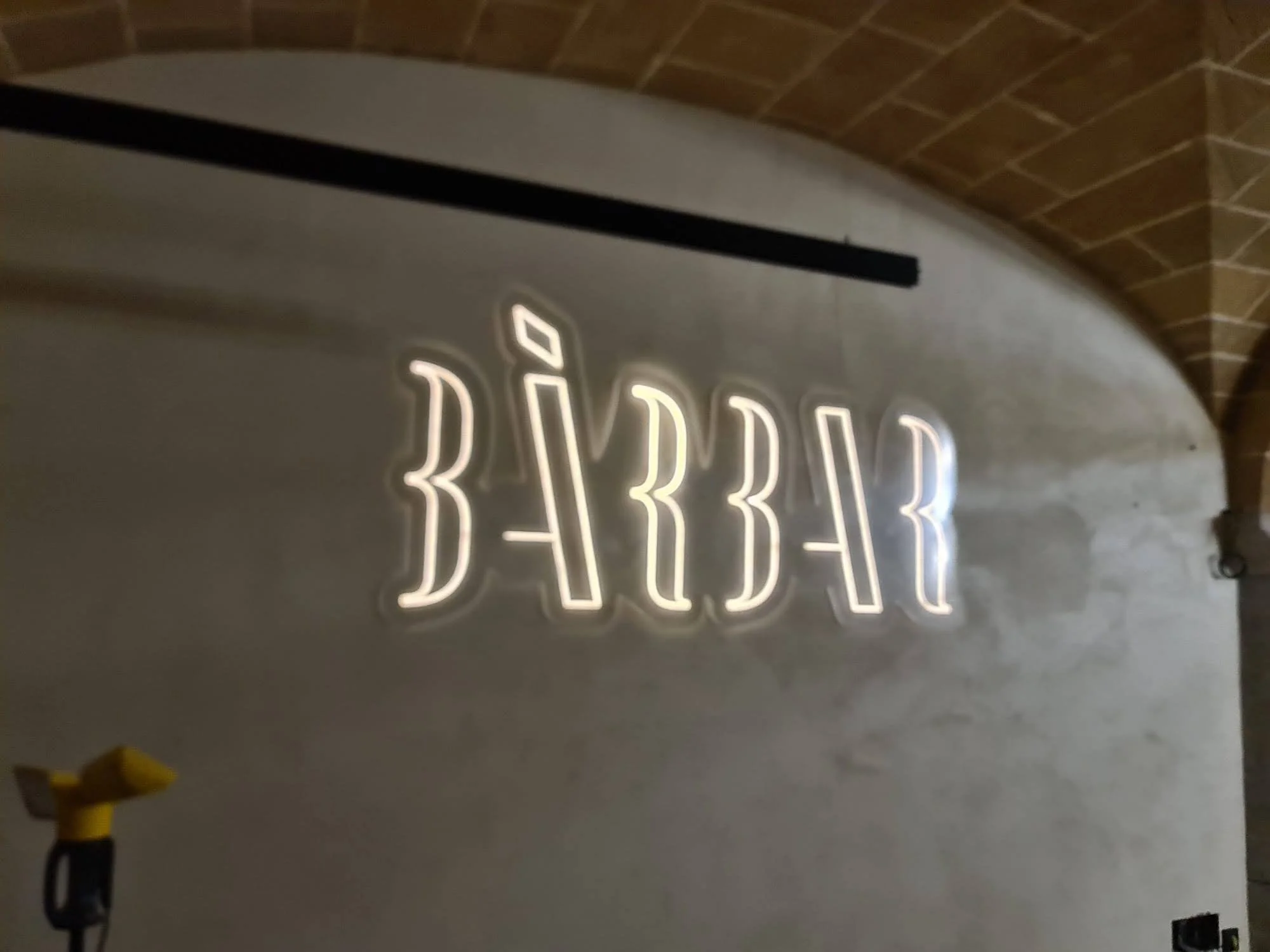 Letras de neón que dicen 'BAR' en una pared de mampostería.