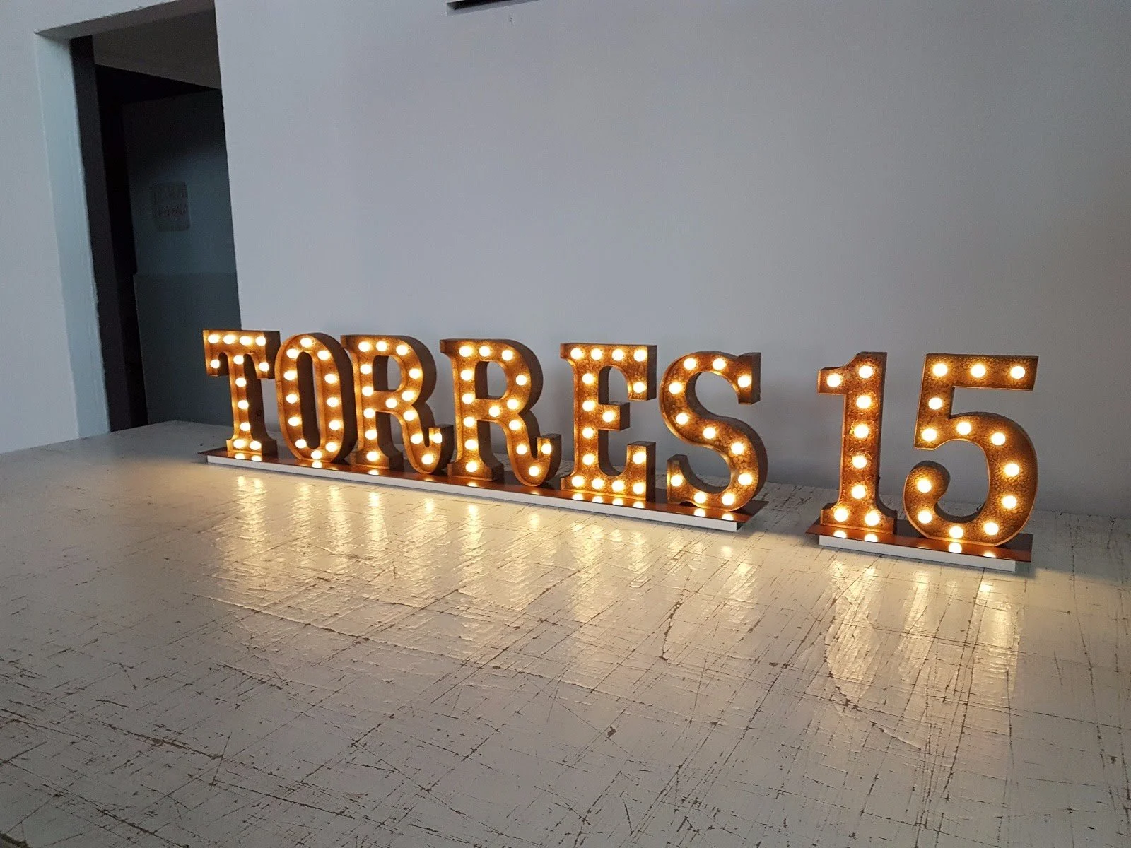 Letrero luminoso que dice 'TORRES 15' sobre una mesa de madera clara.
