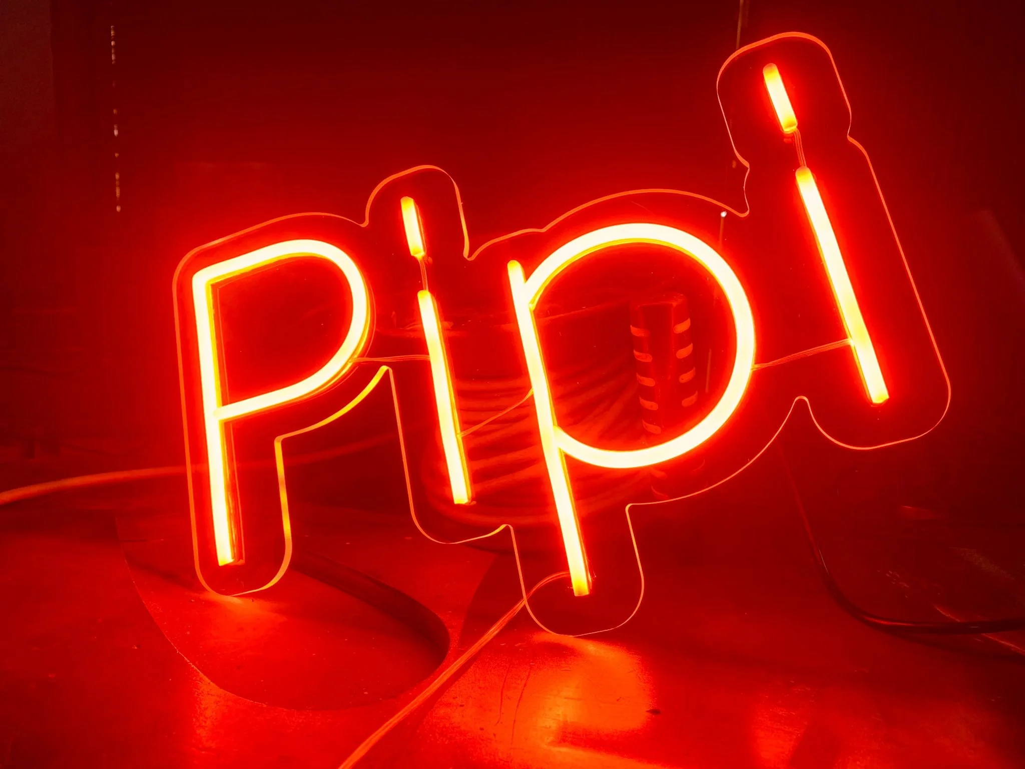 Letrero de neón rojo que forma la palabra 'hot' con letras luminosas y un fondo oscuro.