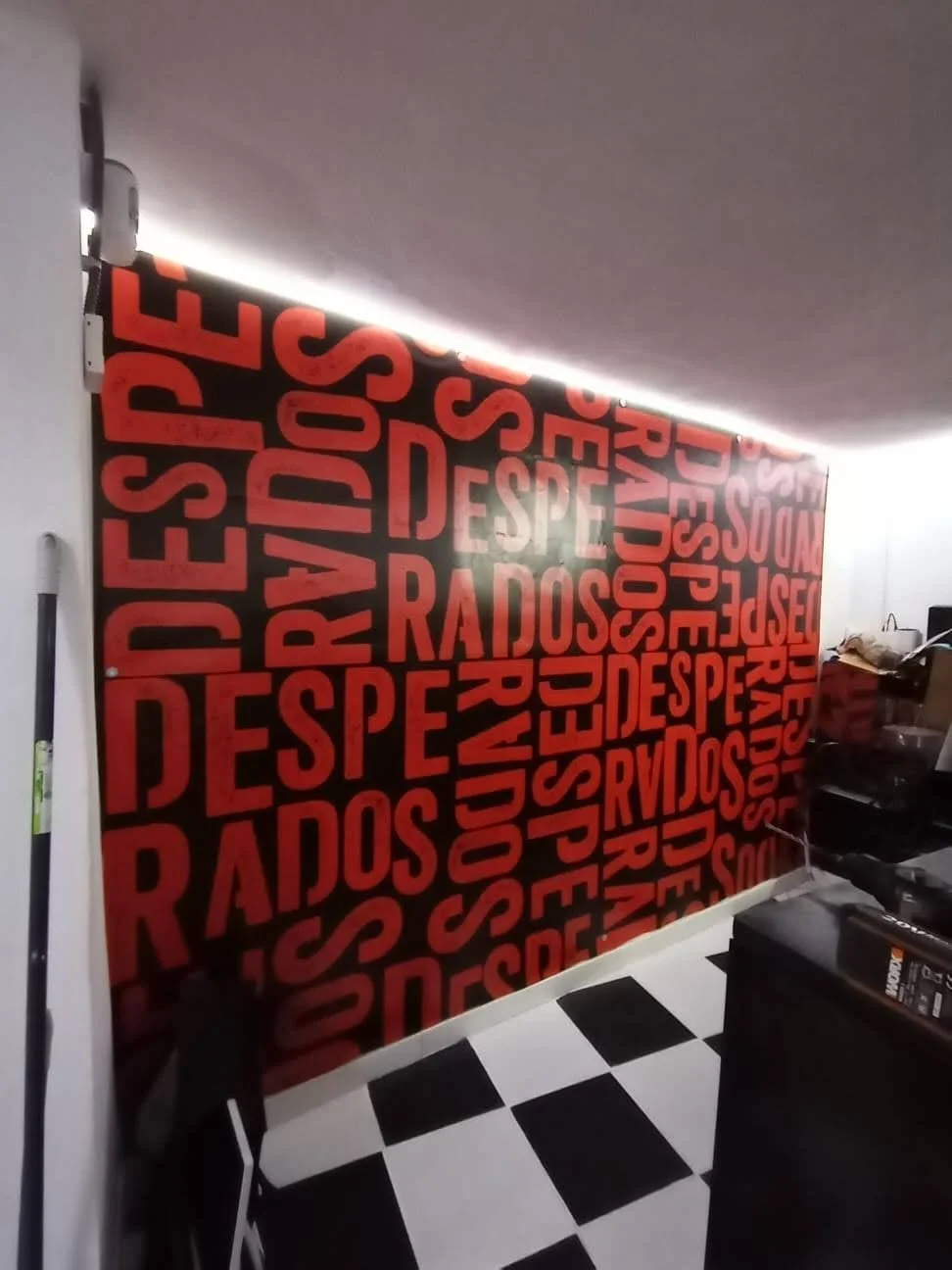 Pared decorada con fondo negro y letras rojas que dicen 'DESPERTARSE' en diferentes orientaciones.