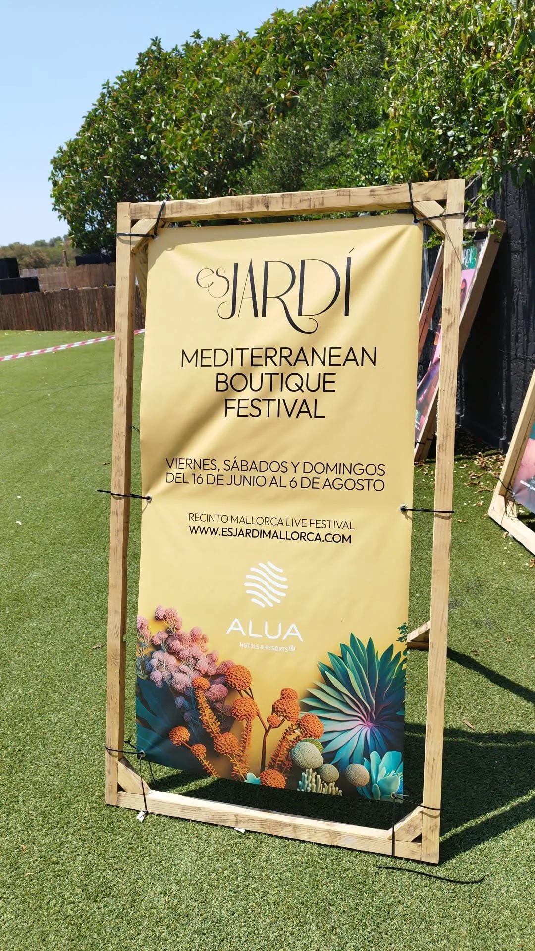 Cartel de anuncio para el festival 'Es Jardí' en Mallorca, con detalles de fecha, lugar y sitio web, y decoración con plantas suculentas y flores.