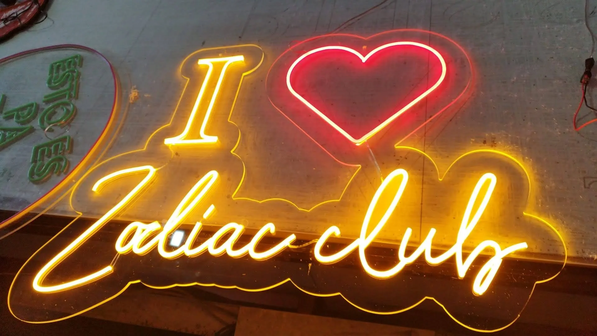 Letrero de neón que dice 'I ❤️ Zadiacu' en colores amarillo, rojo y verde