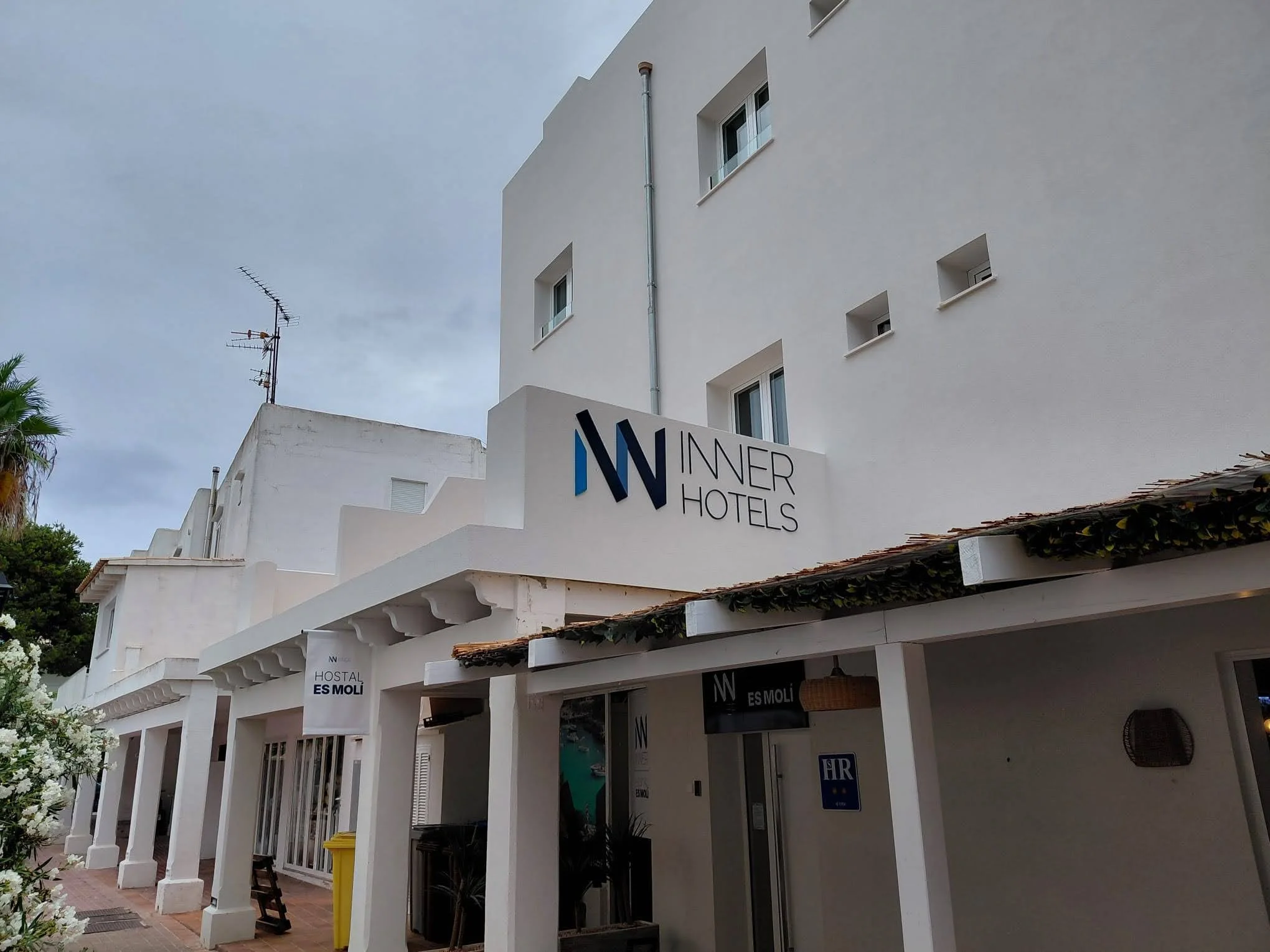 Fachada del hotel Innert Hotels con cartel y ventanas, en un día nublado.