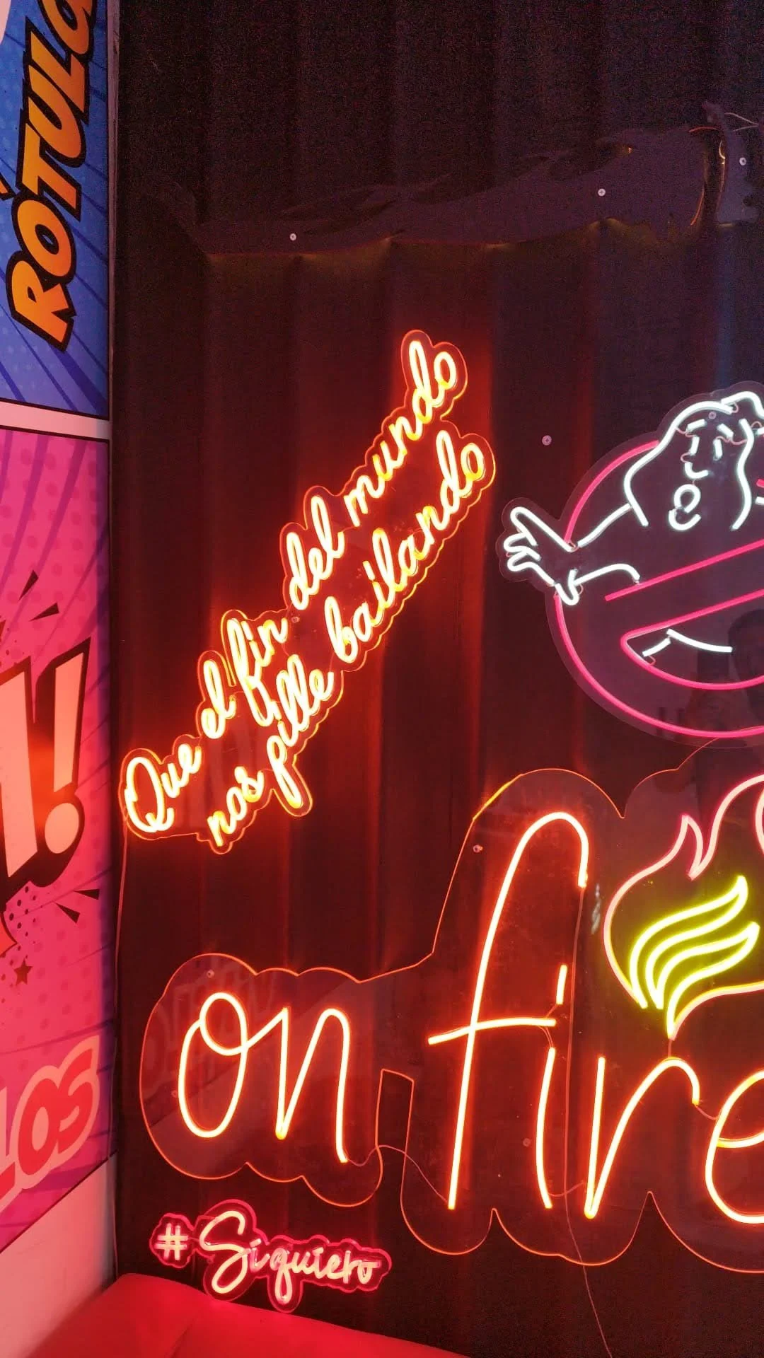 Letras de neón en colores rojos, blancos y amarillos con una frase en español que dice 'Que el mundo no se puede bañar'.