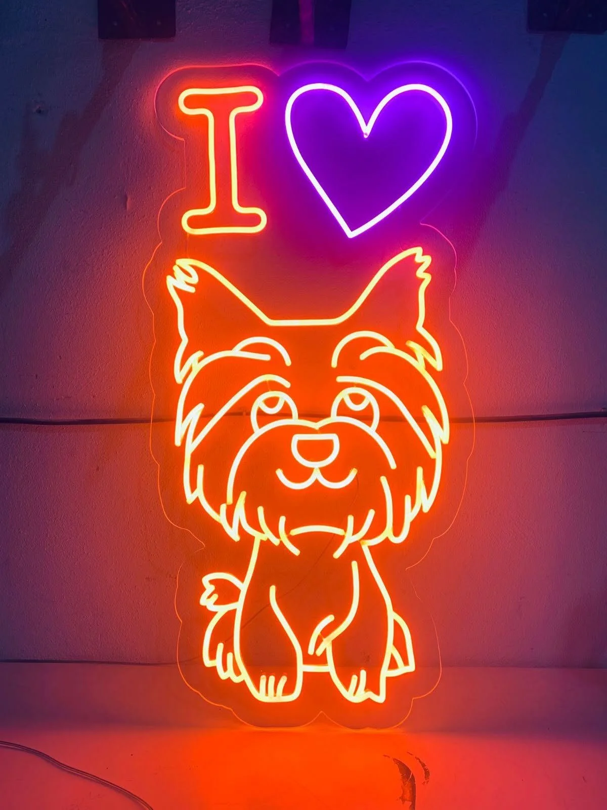 Neón con la frase "I love" en letras rojas y moradas, y un dibujo de un perro feliz en color naranja.