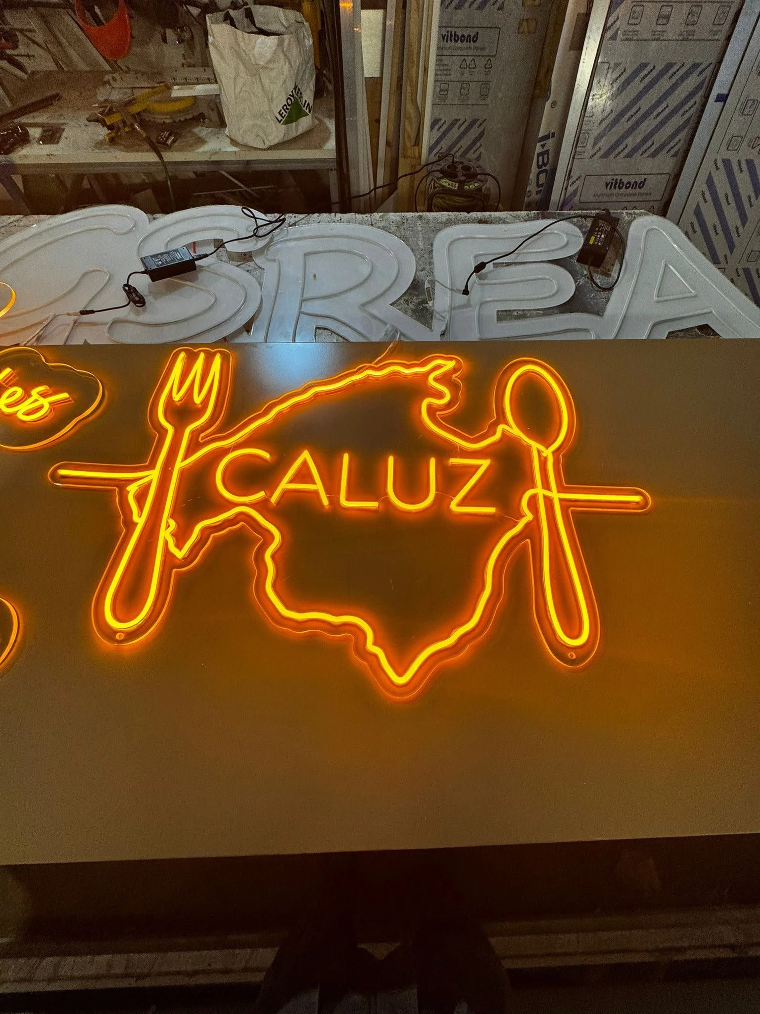 Letrero de neón en forma de mapa de Texas con texto 'CALUZ', y los ingredientes 'queso' y 'mayo' en estilo de neón