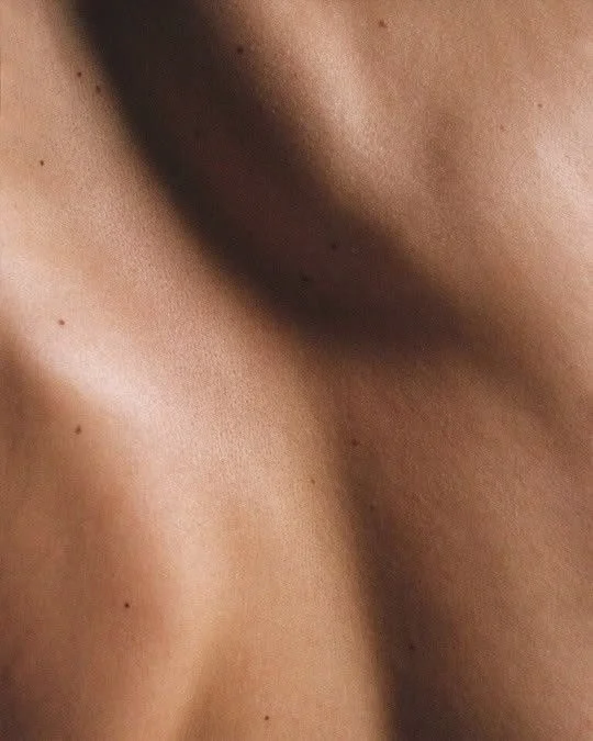 Close-up of smooth, tan skin with small freckles.