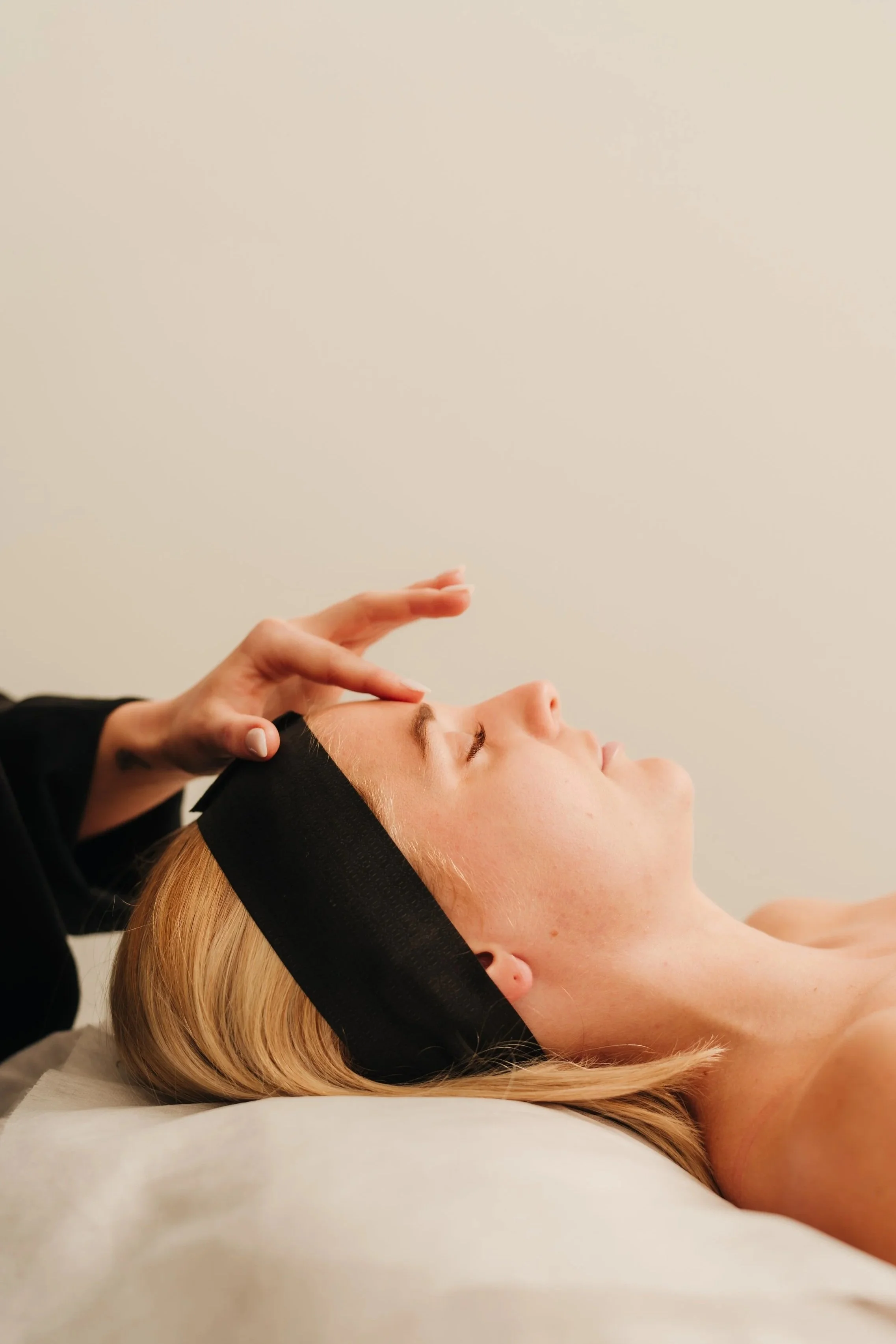 A woman receiving a facial treatment from a practitioner in a spa setting.