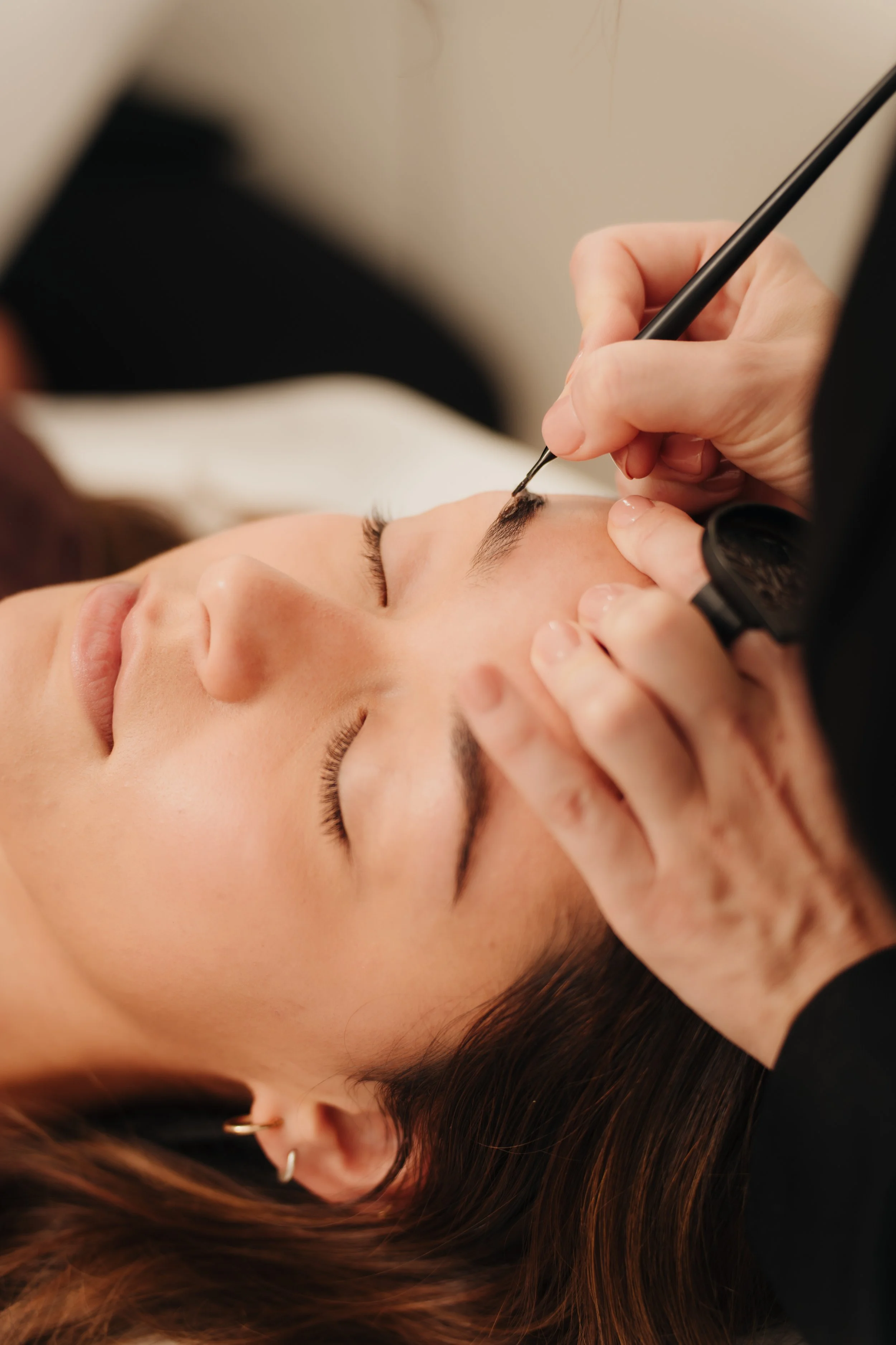 Person receiving an eyebrow tattoo or microblading procedure in a spa or salon.