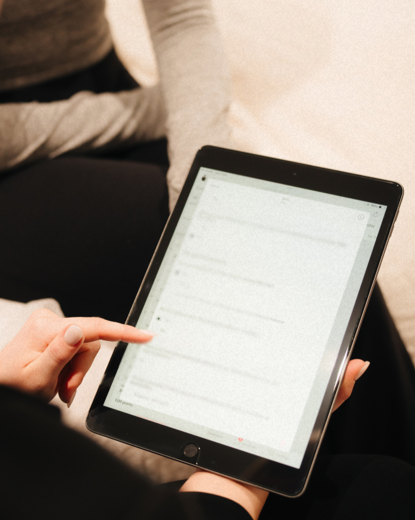 Person holding a tablet with a blurred email or message screen, sitting with another person in a casual setting.