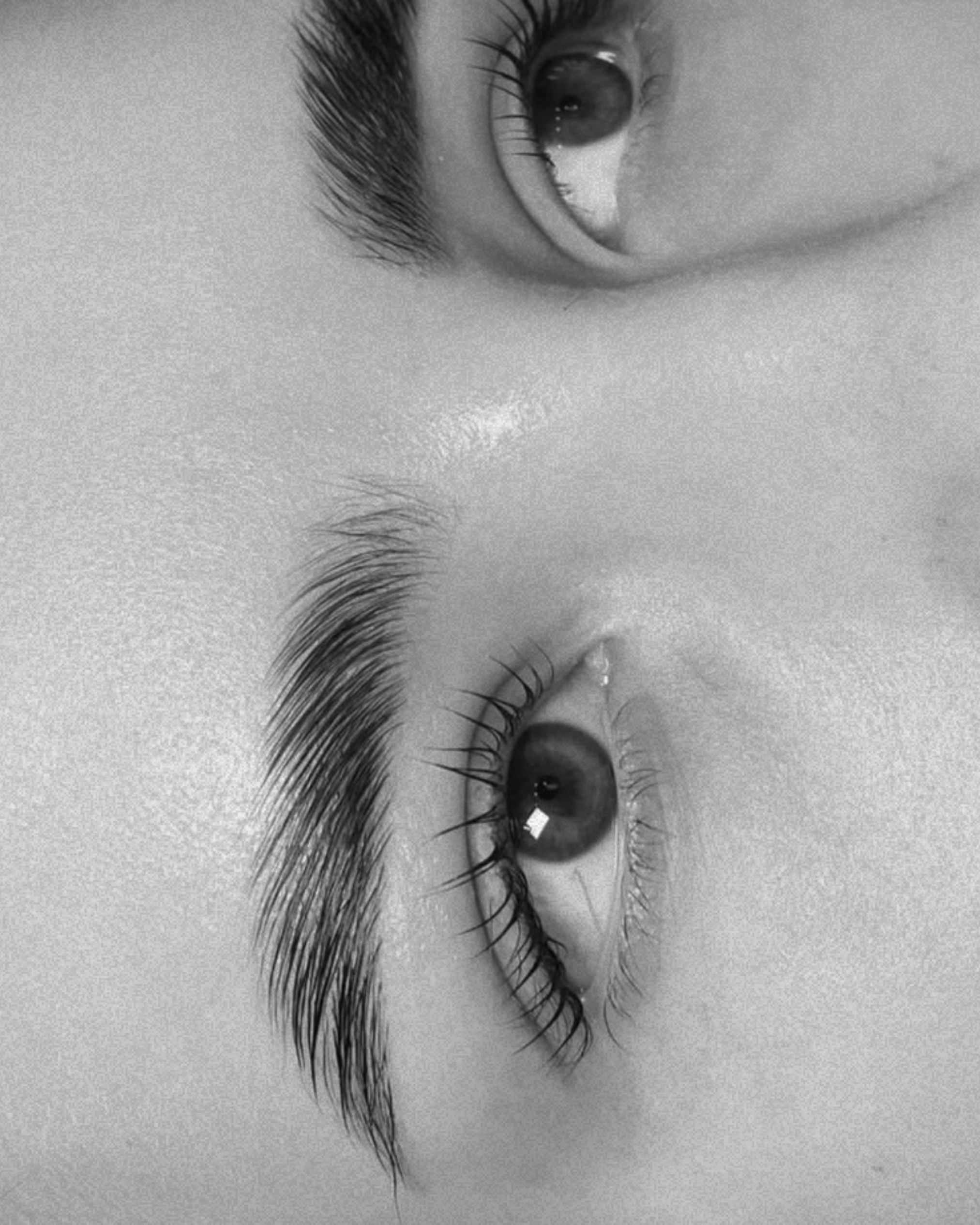 Close-up black and white photo of a person's eyes with water droplets on eyelashes.