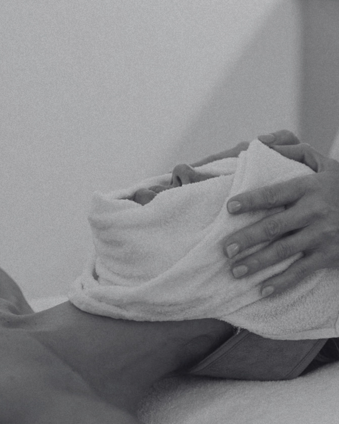 A person holding a newborn baby wrapped in a towel