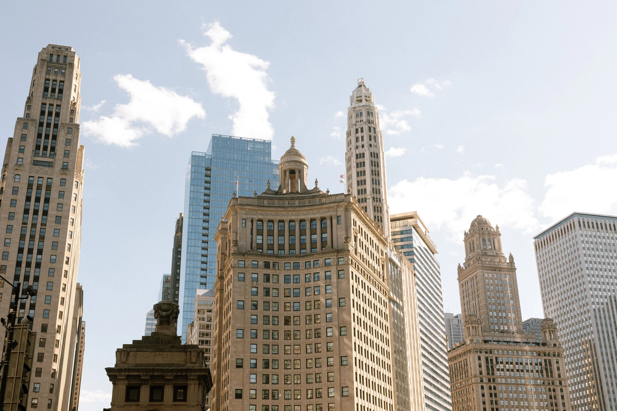 Skyscrapers in a city with a clear blue sky, featuring historic and modern buildings.