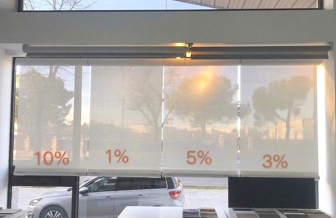 Persianas solares con diferentes niveles de opacidad marcados como 10%, 1%, 5%, y 3%, en una ventana con vista a la calle y un coche estacionado afuera.