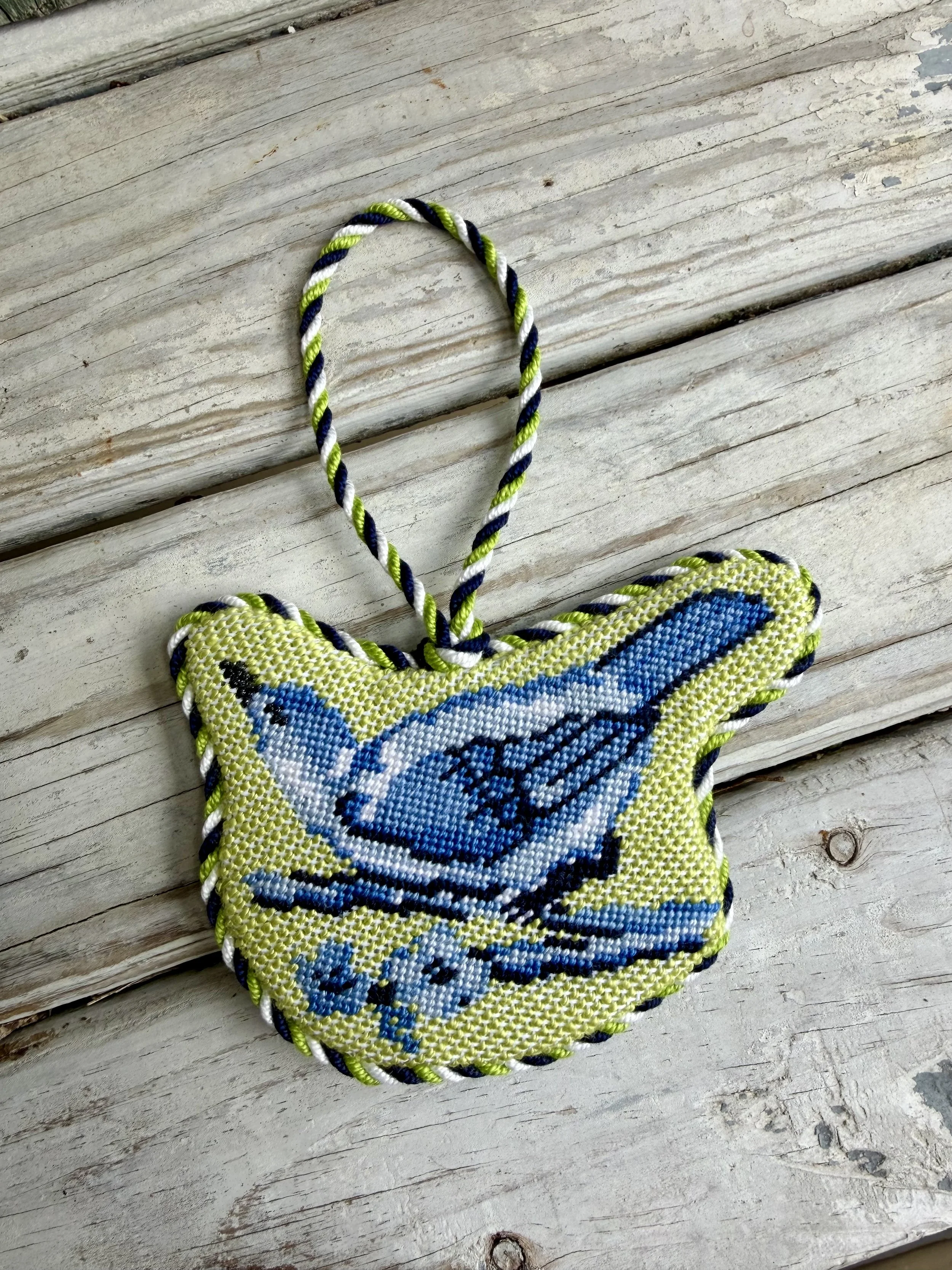Irregular shaped Needlepoint Ornament of a blue bird. Custom cording. Finished with The Salty Stitchery