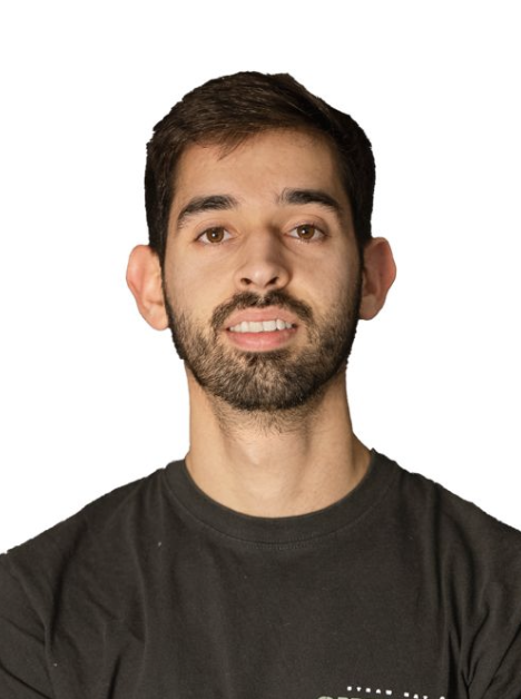 Portrait of a young man with dark hair and a beard, wearing a black T-shirt, against a white background.