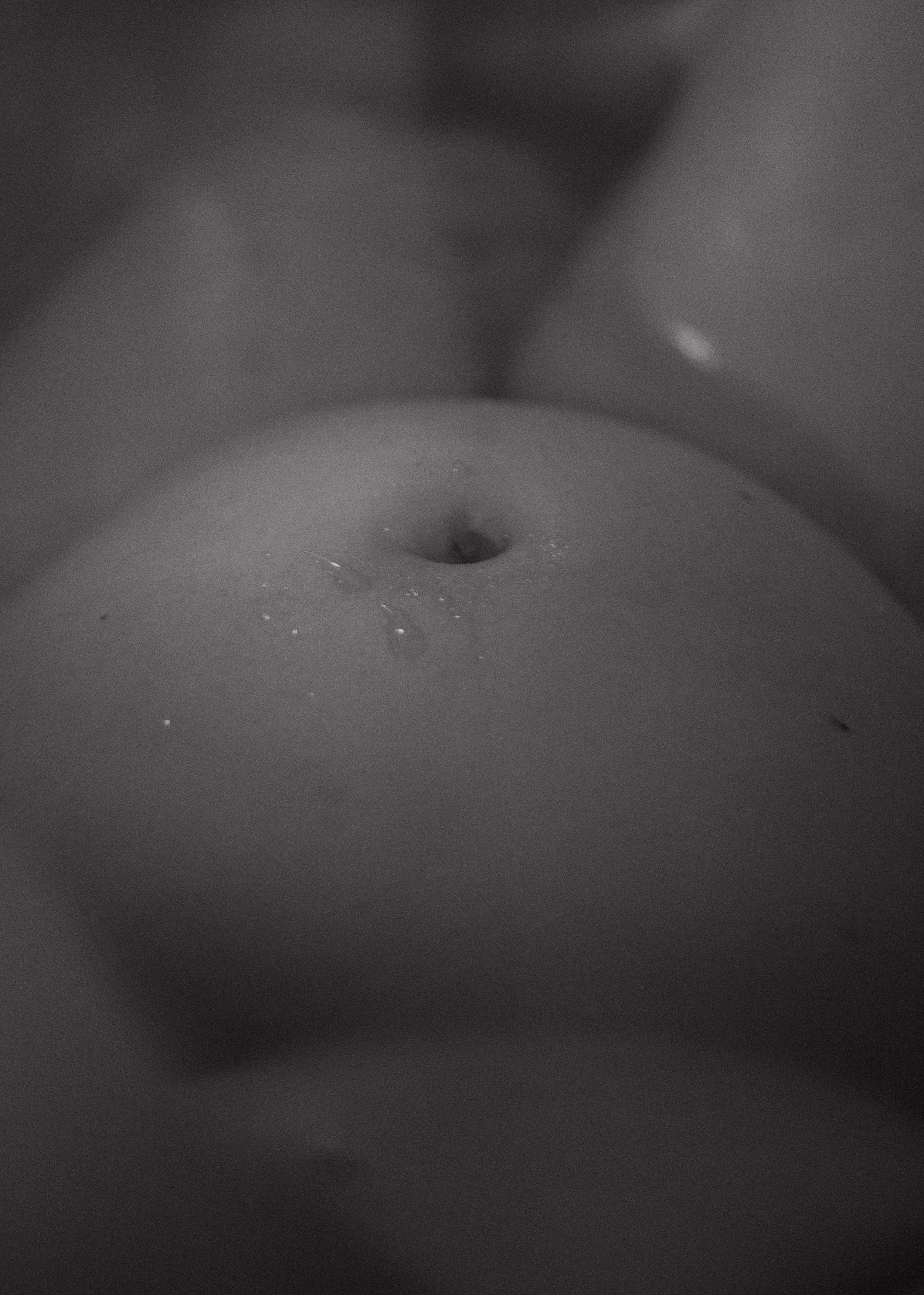 Nahaufnahme eines Bauchnabels auf nackter Haut in Schwarz-Weiß