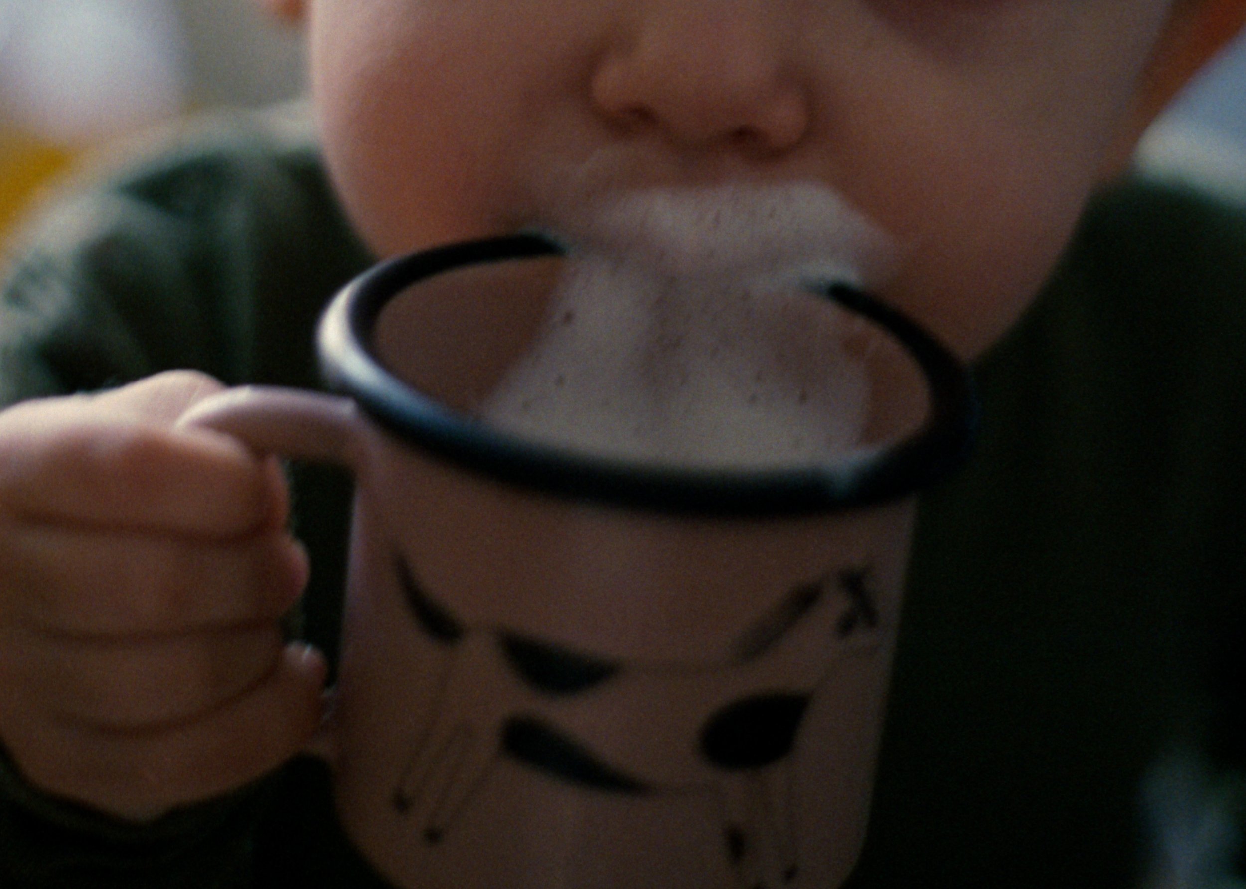 Ein Kind trinkt aus einer Tasse, dabei sieht man nur den Mund voller Milchschaum