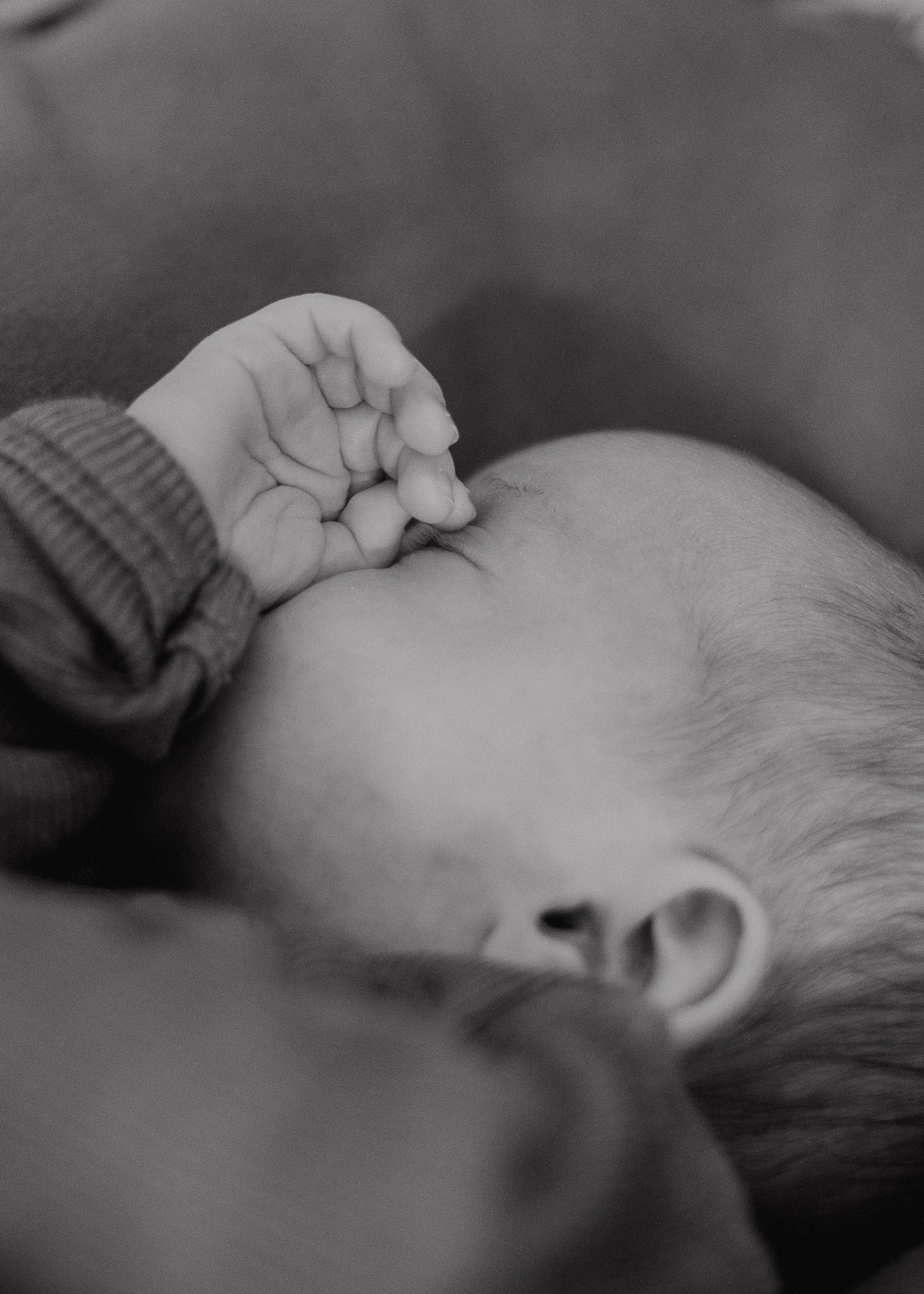 Ein kleines Kind liegt im Bett und trinkt Milch aus der Brust einer erwachsenen Person.