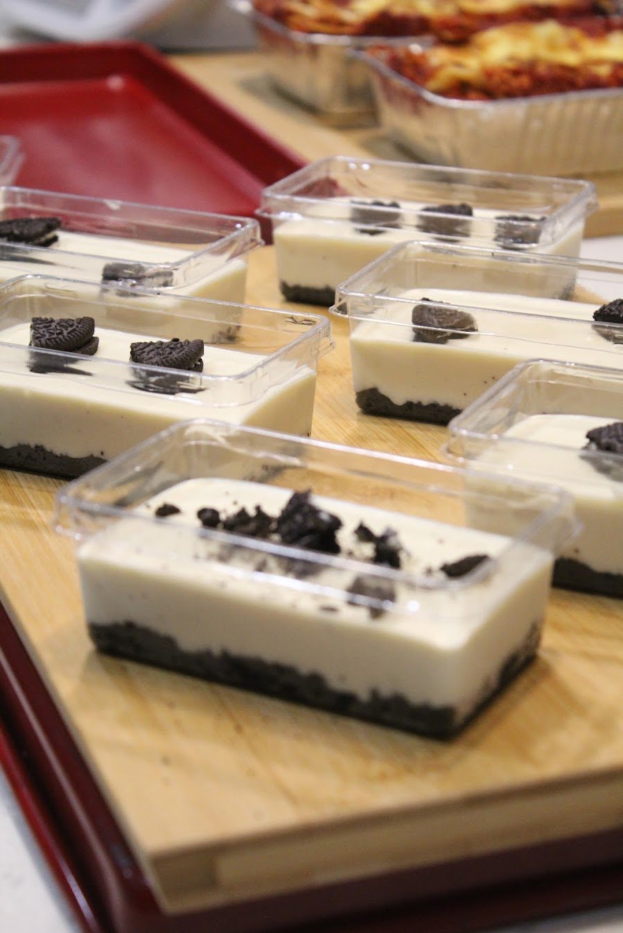 Lactose-free cookies and cream cheesecake in tubs, with a dark cookie base and cookie pieces on top