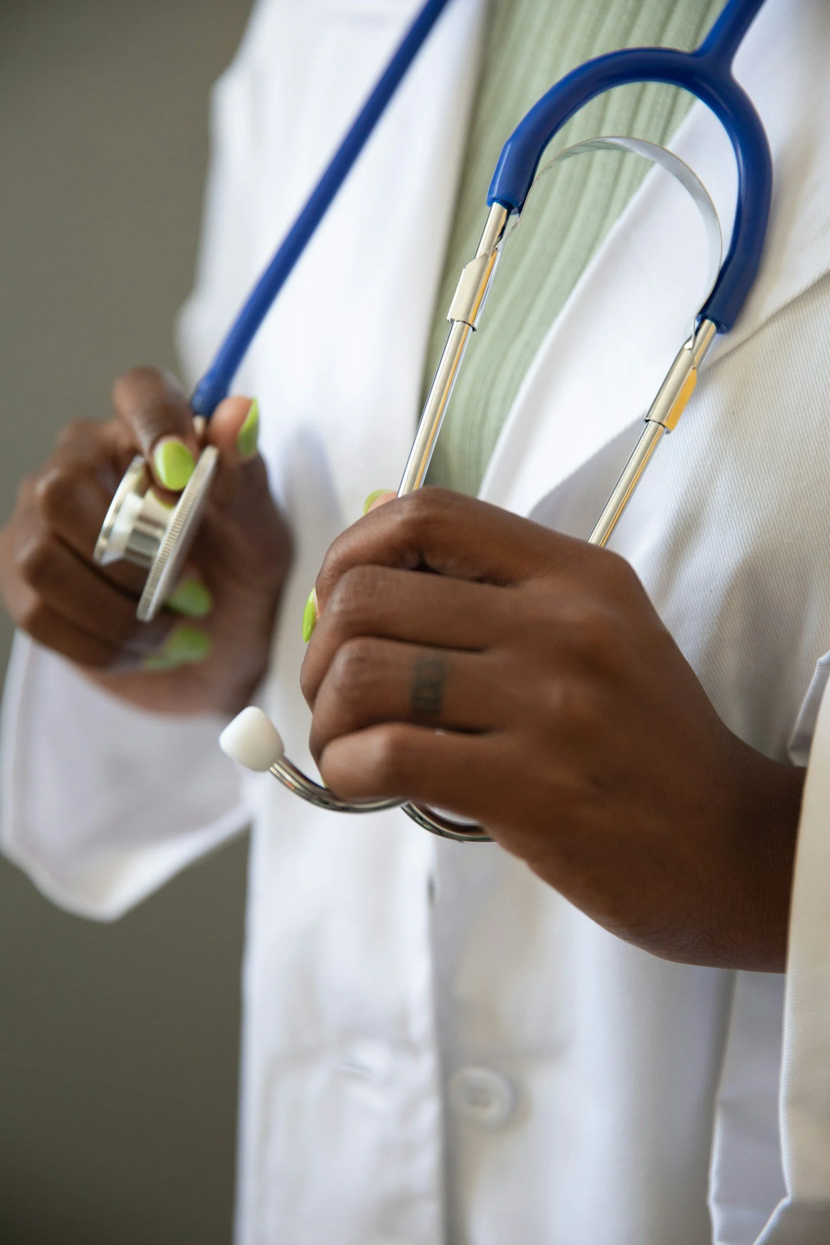 Close-up of a healthcare professional holding a stethoscope and wearing a white lab coat.